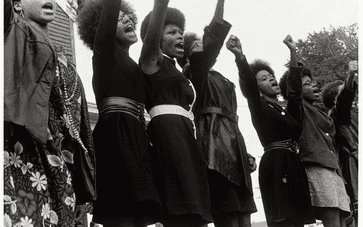 A black and white photograph of six African American women at a Black Panther rally.