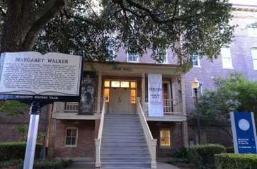Brick building labeled “Ayer Hall” with banners and a Margaret Walker historical marker under a large tree.