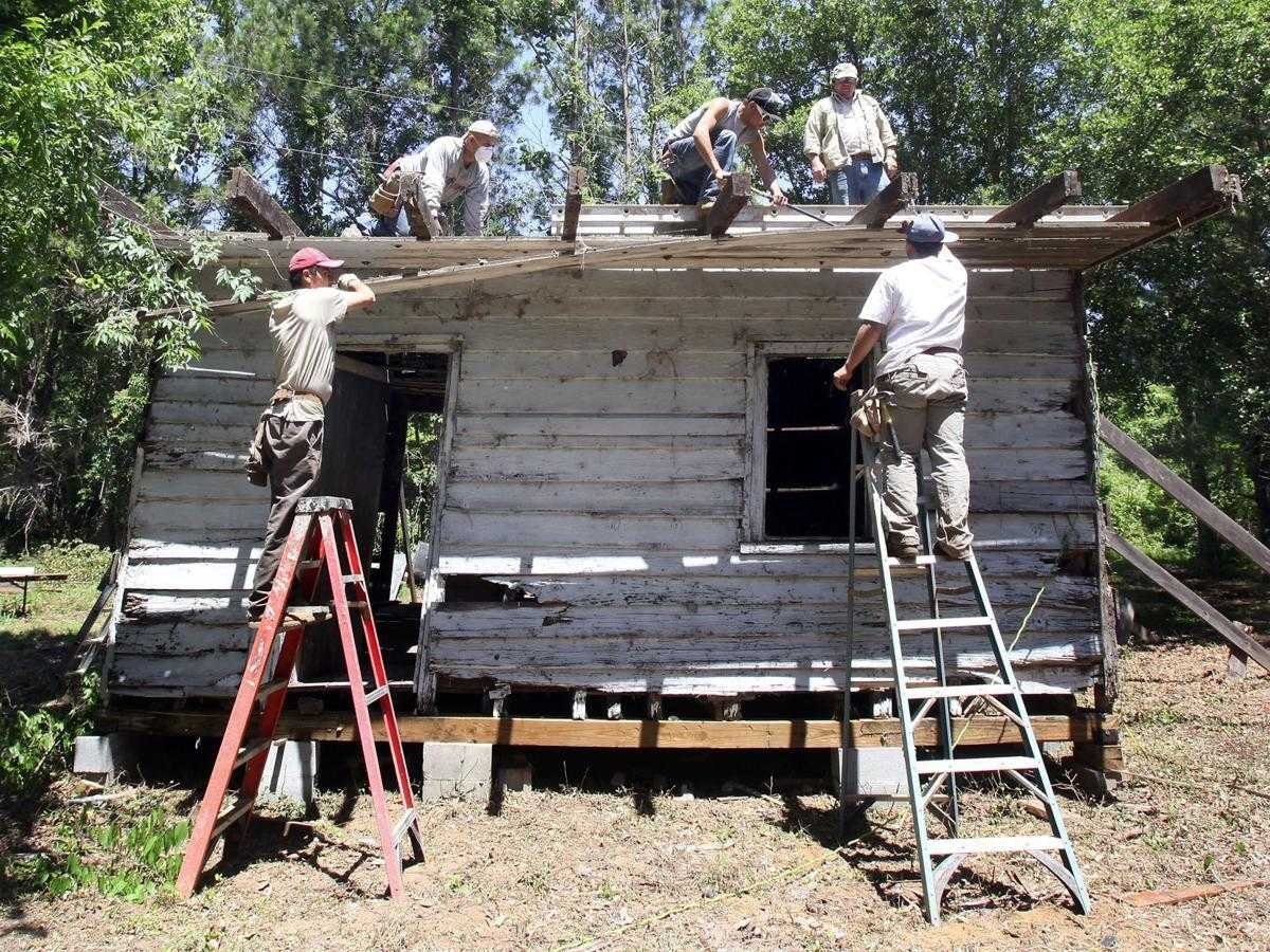 Photograph of people dismantling cabin