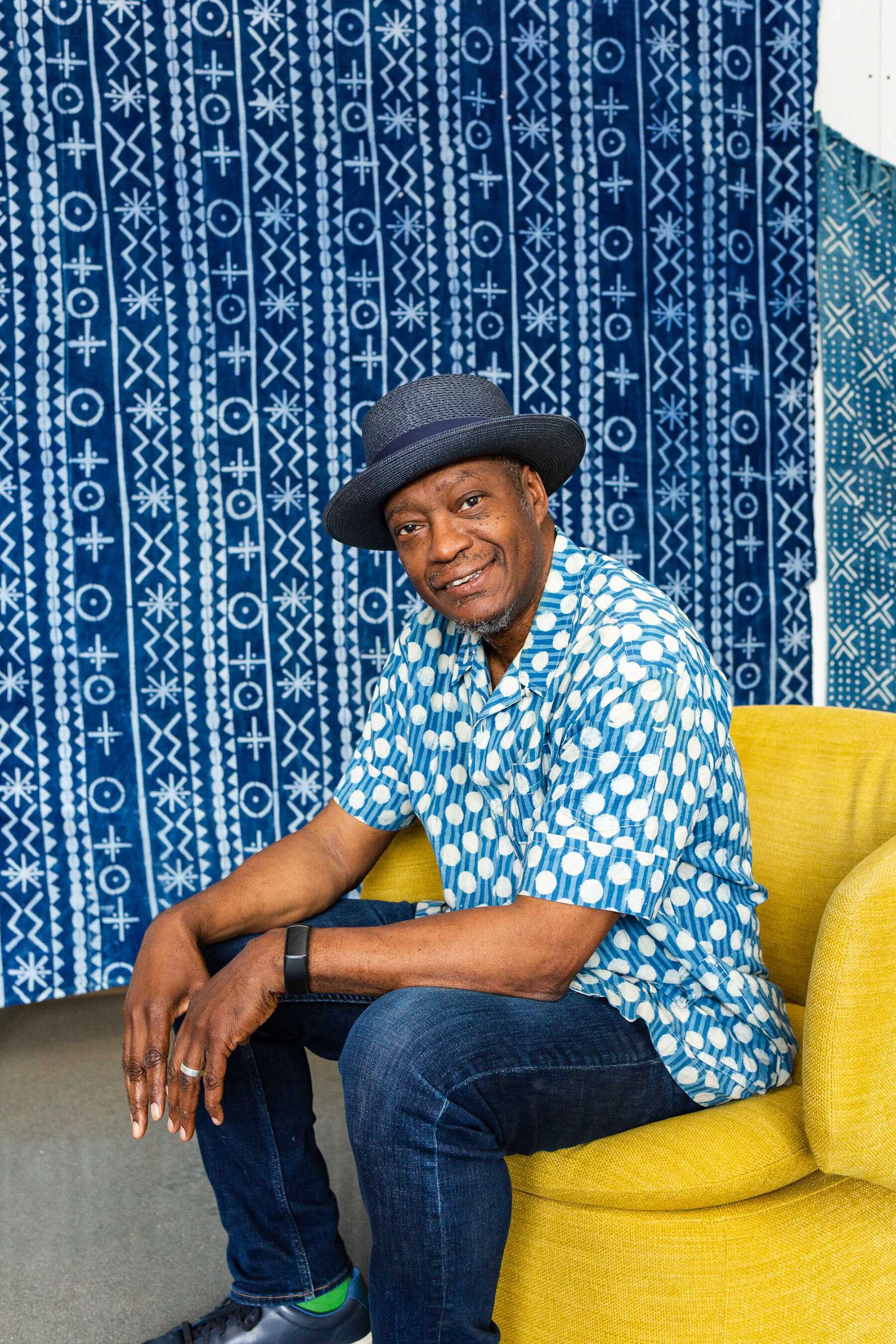 Color photograph of artist Daniel Minter seated in a yellow chair.