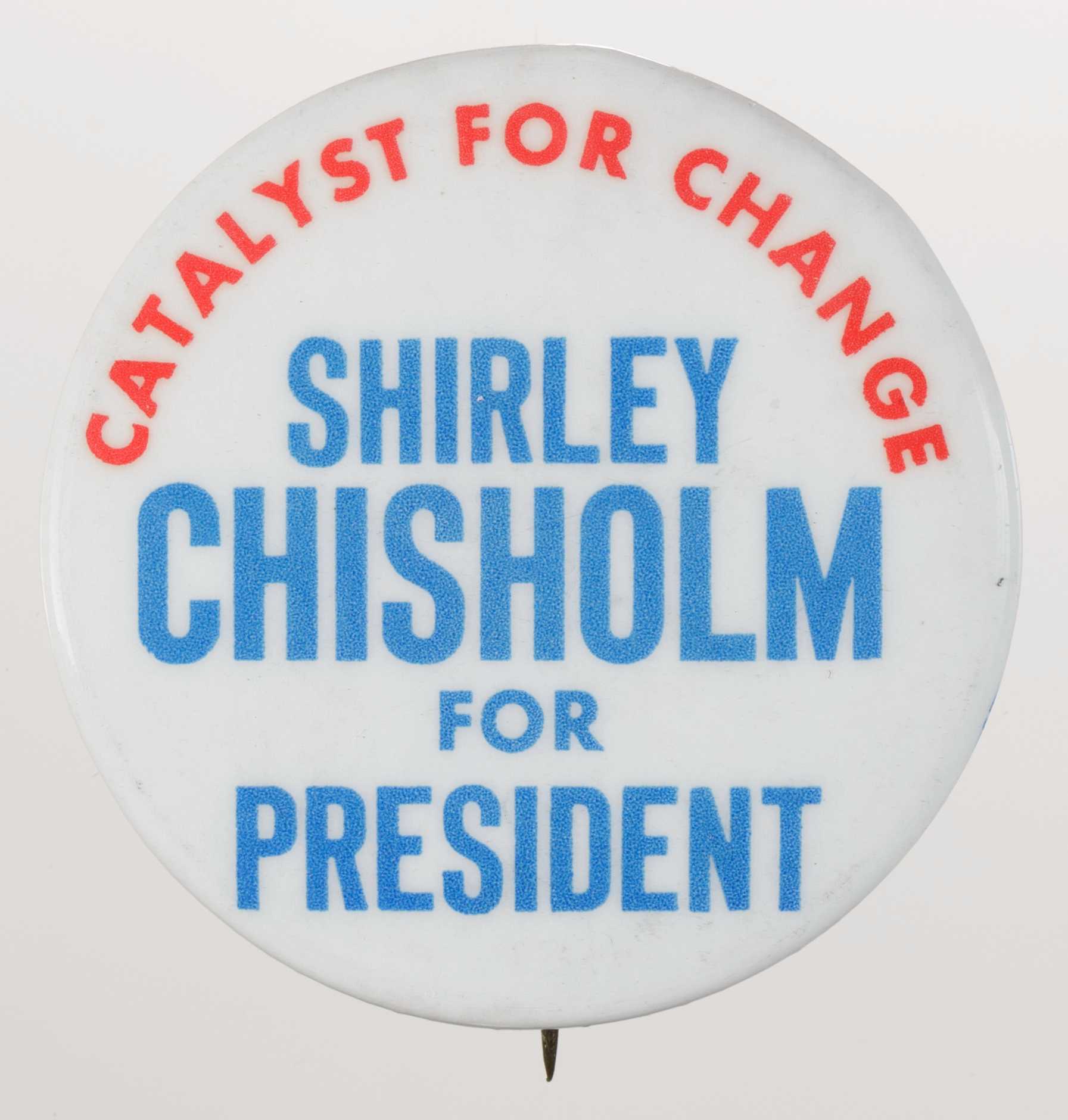 A circular metal pin-back button. The button has a white background with blue and red type that reads: [CATALYST FOR CHANGE] around the top in red, and [SHIRLEY / CHISHOLM / FOR / PRESIDENT] in blue, centered below. The edge of the pin reads in blue text: [Columbia Advertising Company 133-14 101 Richmond Hill, NY 11419]. Next to the text is a logo in blue print followed by the number [9]. The back of the button is silver in color, has a single pin without a clasp and an engraving. The engraving has a circular symbol with the word Union on one side.