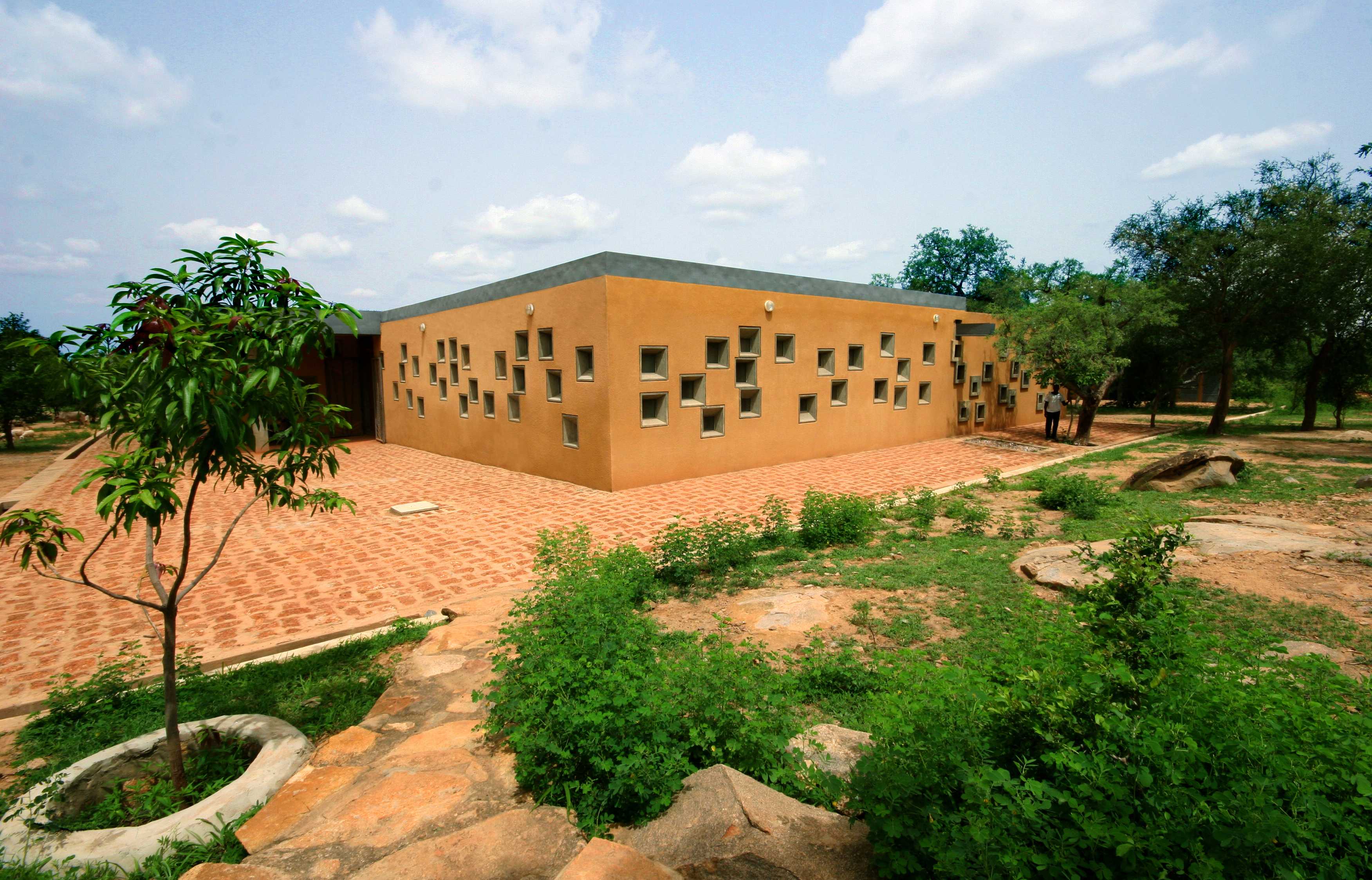 The centre for Health and Social Welfare is a tan, one level building with randomly placed square windows.