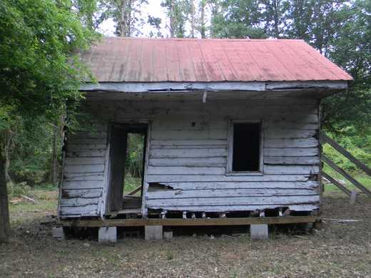 The cabin is a one-story, two-room, rectangular, weatherboard clad building with an extended side gable roof which acts as the overhanging porch roof and a brick /masonry fireplace on the west elevation. The structure is a timber frame, meaning a heavy timber mortise and tenon, structure. It is composed of 6”x 6” sills of Southern Yellow Pine, 3” x 4” studs with 4” x 6” braces, topped with 4” x 6” plates and 3” x 4” rafters all of Southern Yellow Pine. Rafters are covered with lath and the structure originally had a cypress shingle roof; some pieces of shingles survive in the roof frame. The exterior was covered by Southern Yellow pine lap siding and painted with whitewash.