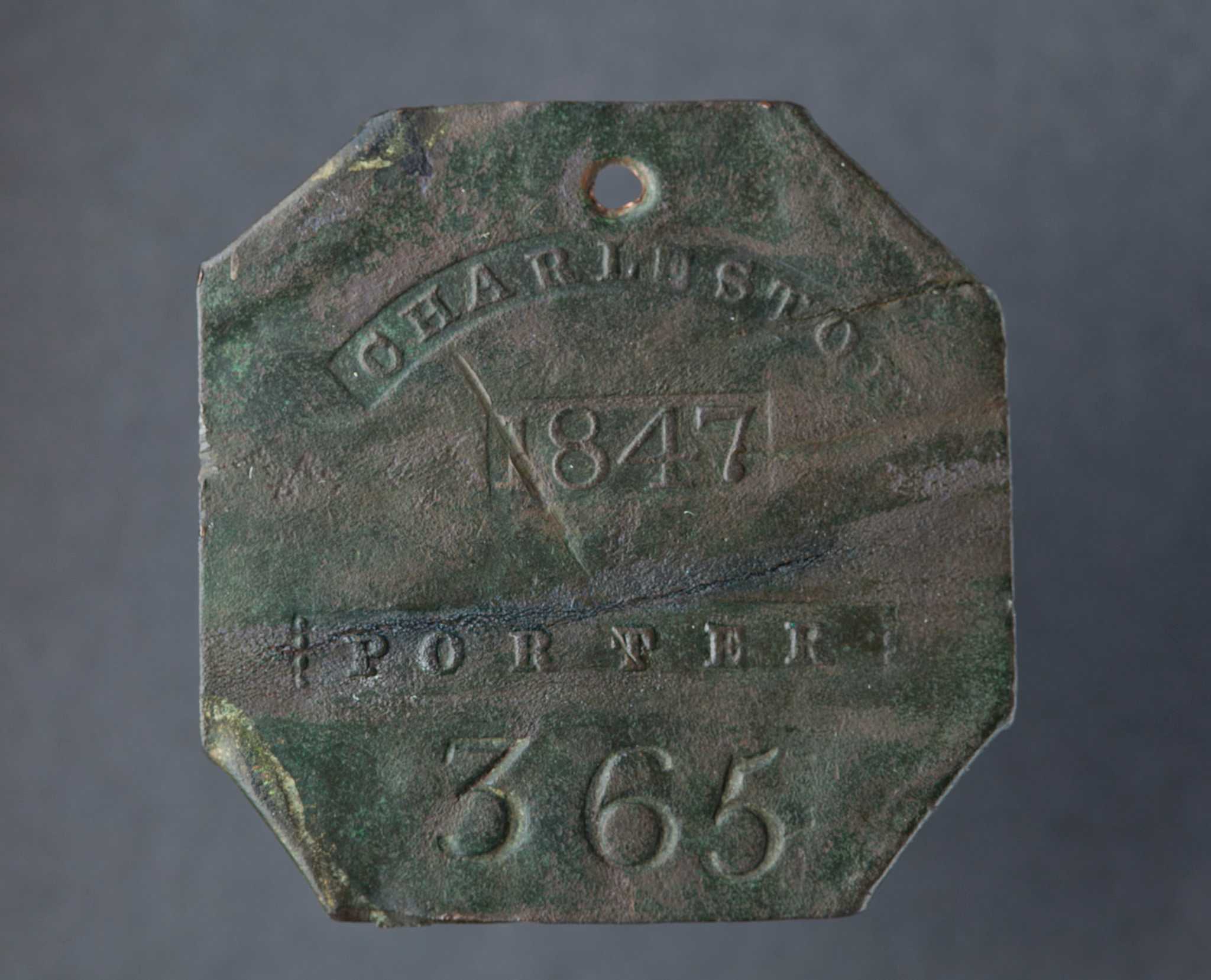 Discolored copper square with corners folded behind and an attachment hole on the top. Die stamped: "CHARLESTON / 1847 / PORTER / 365."