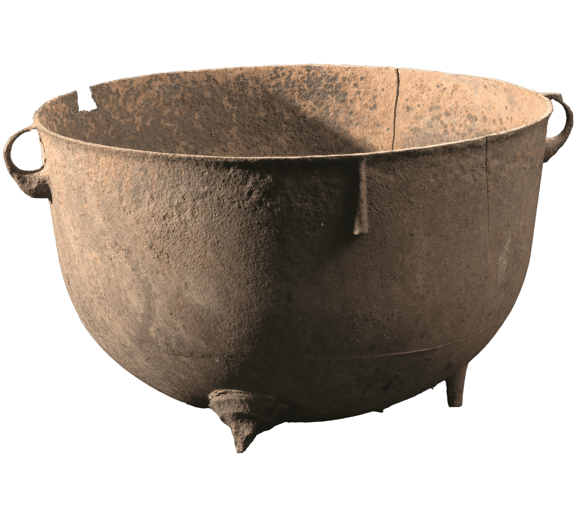 A large wash pot has small handles and small feet. It is worned from rust and dirt and cracked.