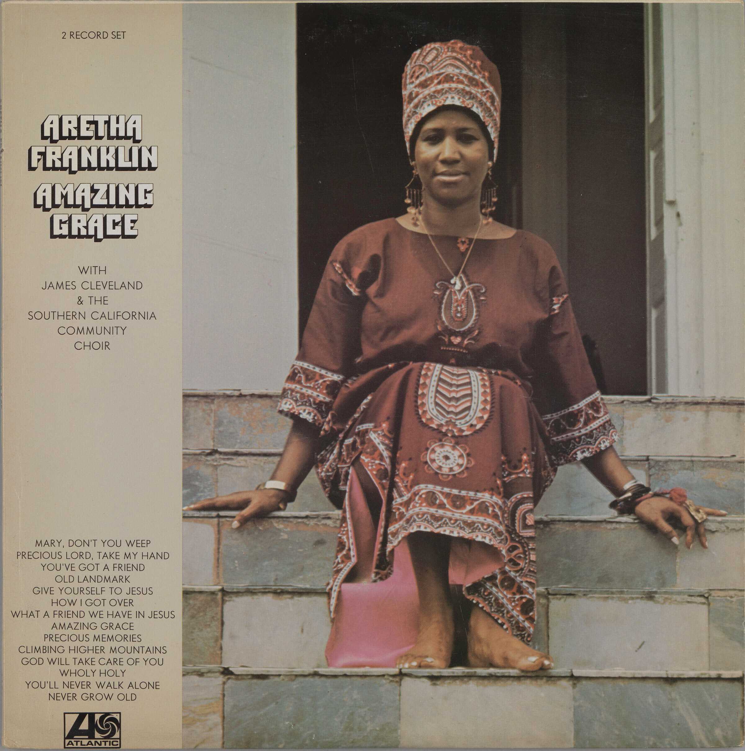 Image of the album jacket for Aretha Franklin's album Amazing Grace, featuring an image of Aretha Franklin sitting barefoot on steps in a pink dress and head wrap.