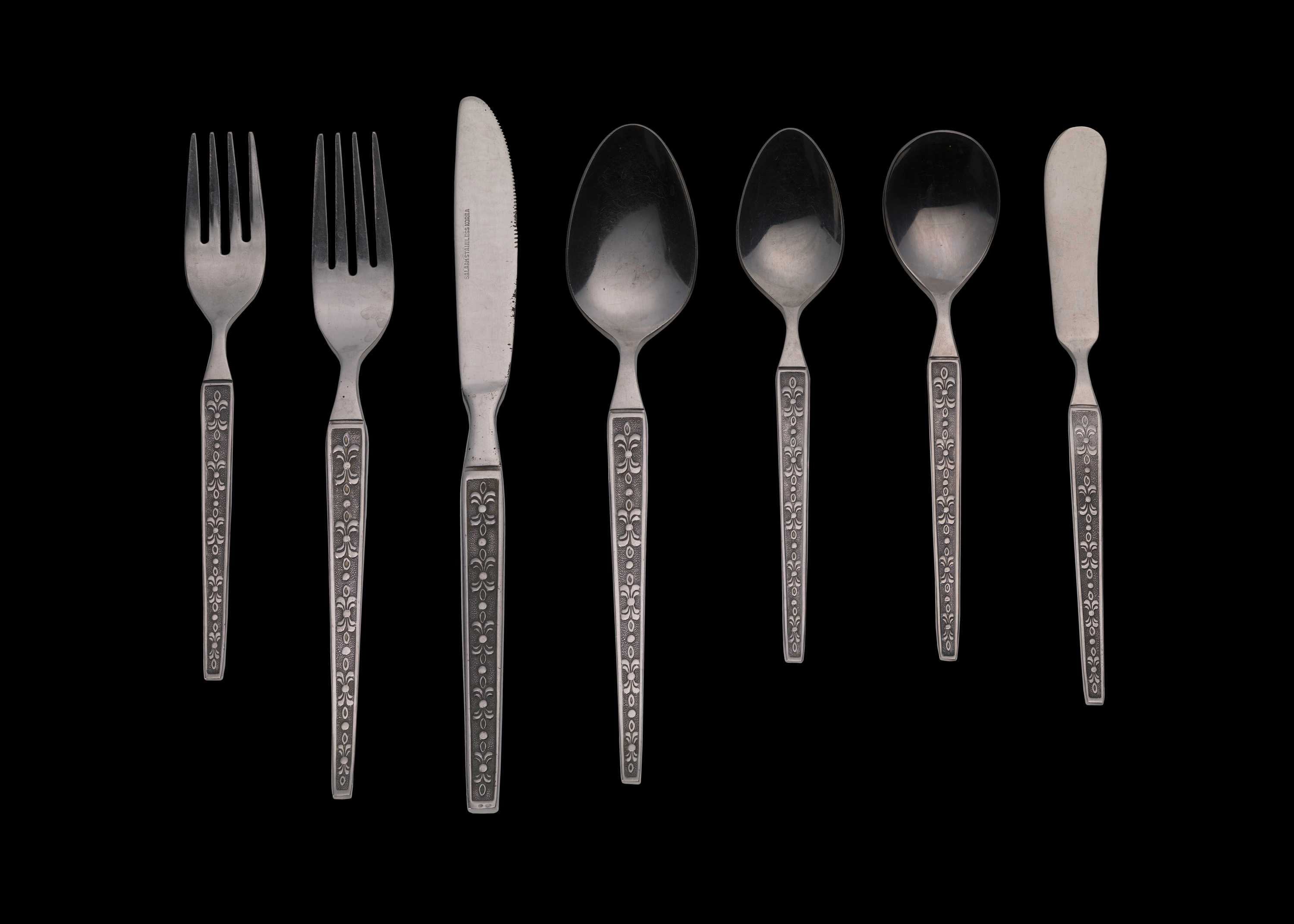 Photograph of Seven (7) piece place setting of stainless steel flatware purchased from Salaam International in Chicago, Illinois, in 1972 by Khalid and Patricia Al Amin.