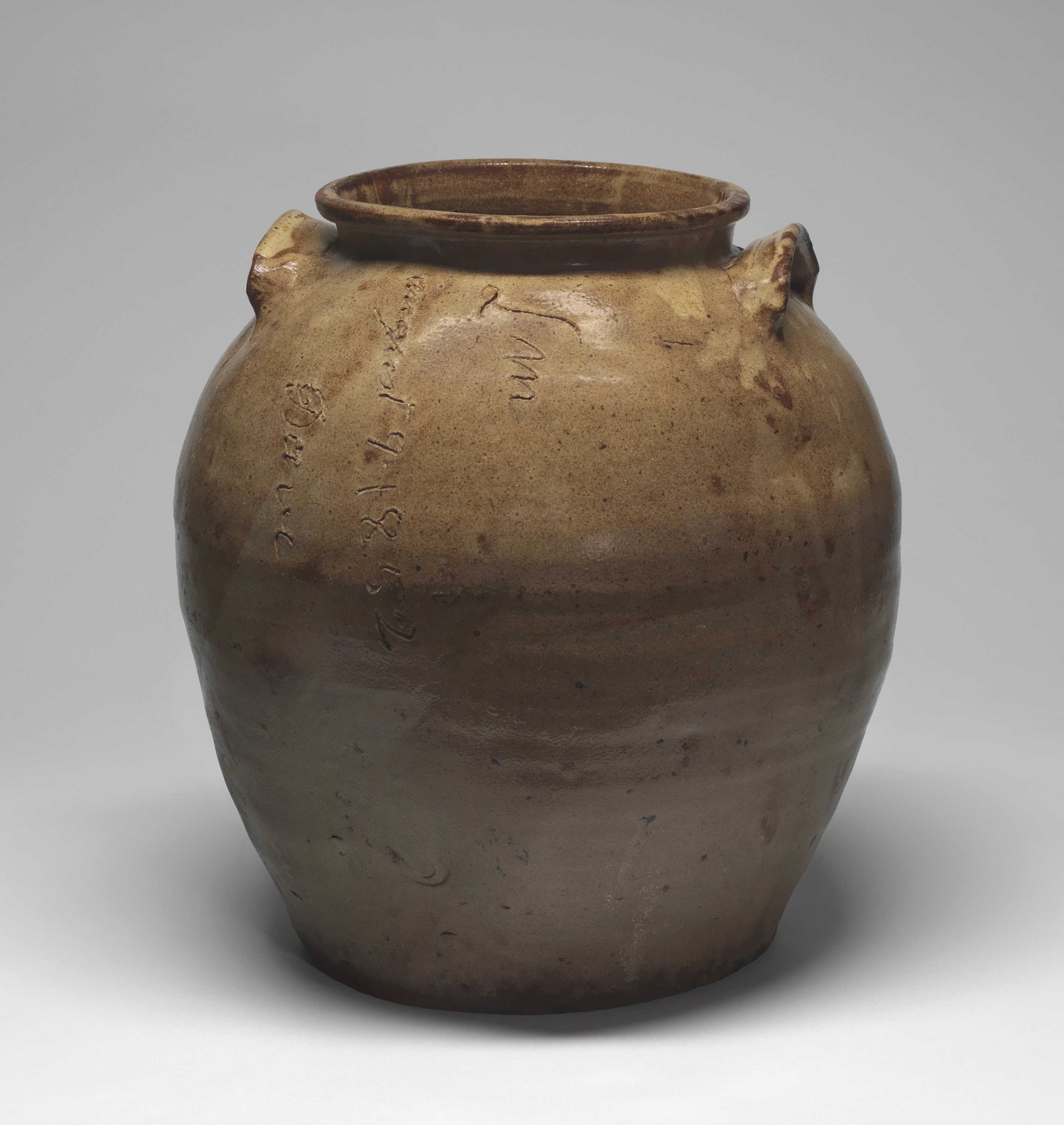 Brown colored jar with two small handles on the upper portion of body near rim. Signed and dated by artist vertically at upper body.