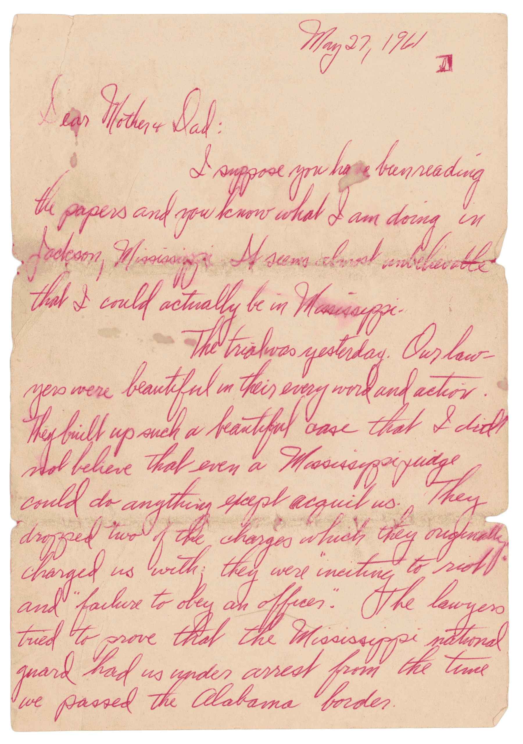 The first page of a handwritten letter by John Moody to his parents on May 27, 1961. It is written in red pen on white paper and is about the May 1961 Freedom Ride.