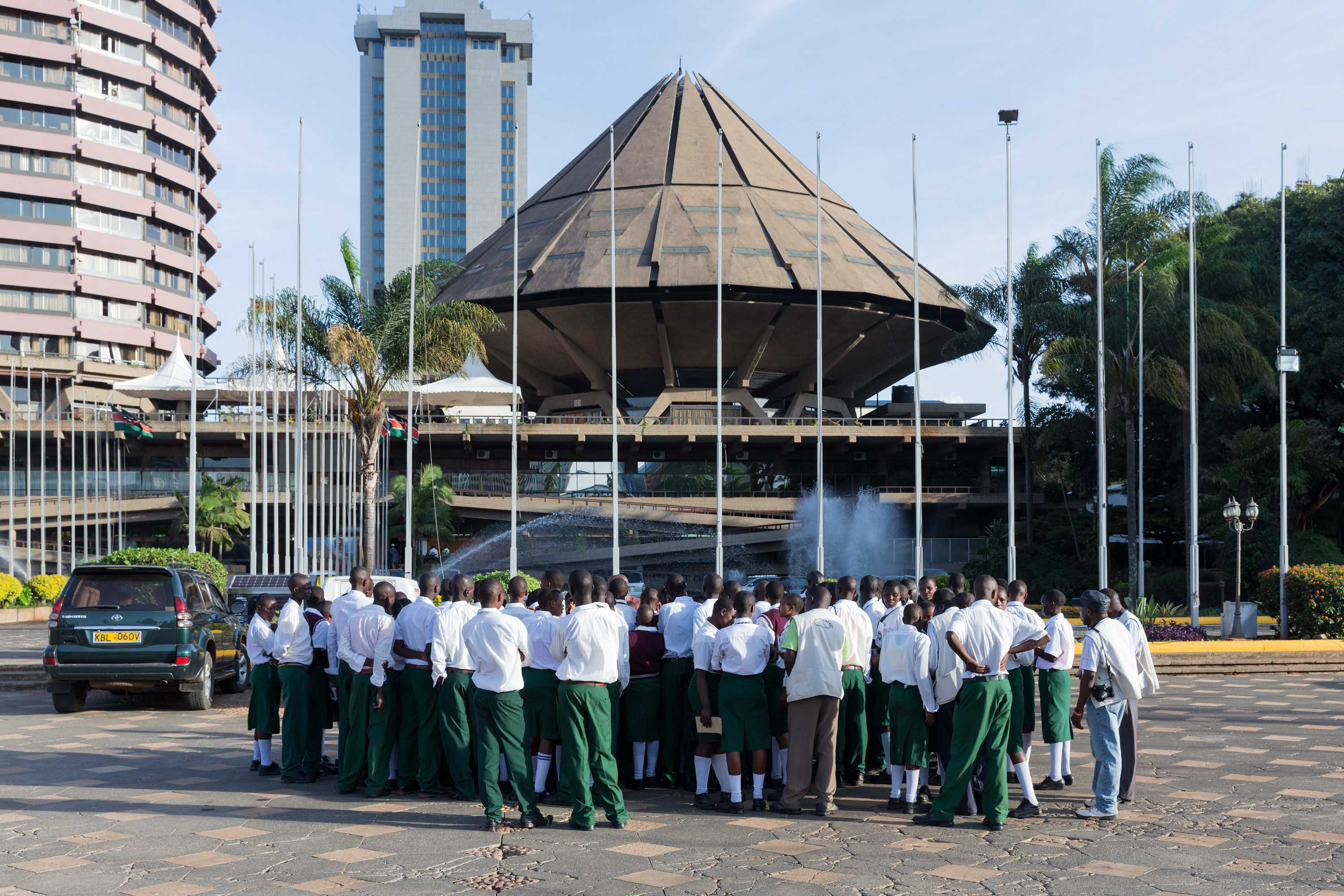 A group of school children standing outside, looking at the Kenyatta International Conference Centre.