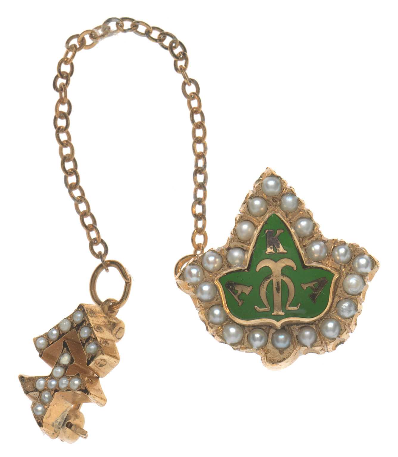 An Alpha Kappa Alpha members badge with a stickpin back. The badge is in the shape of an ivy leaf with a green center.