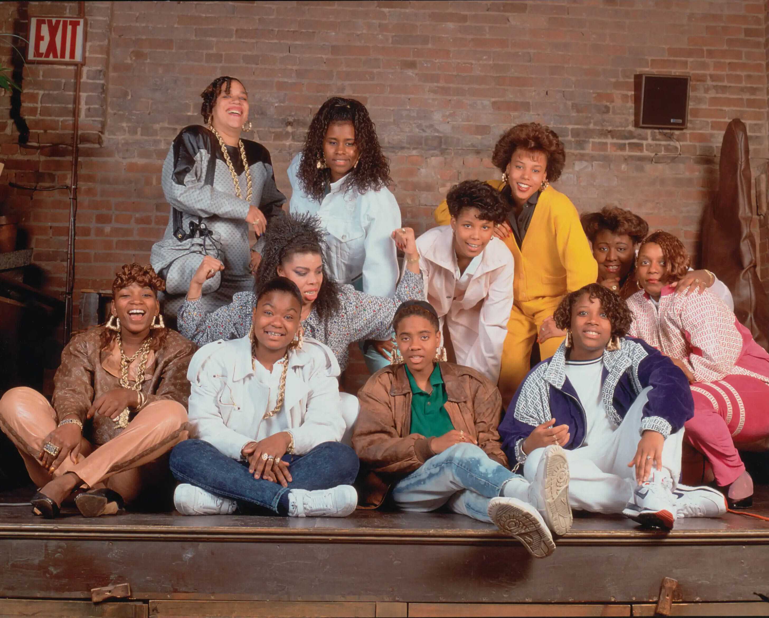 Color photograph of female rappers seated, kneeling and standing on a stage