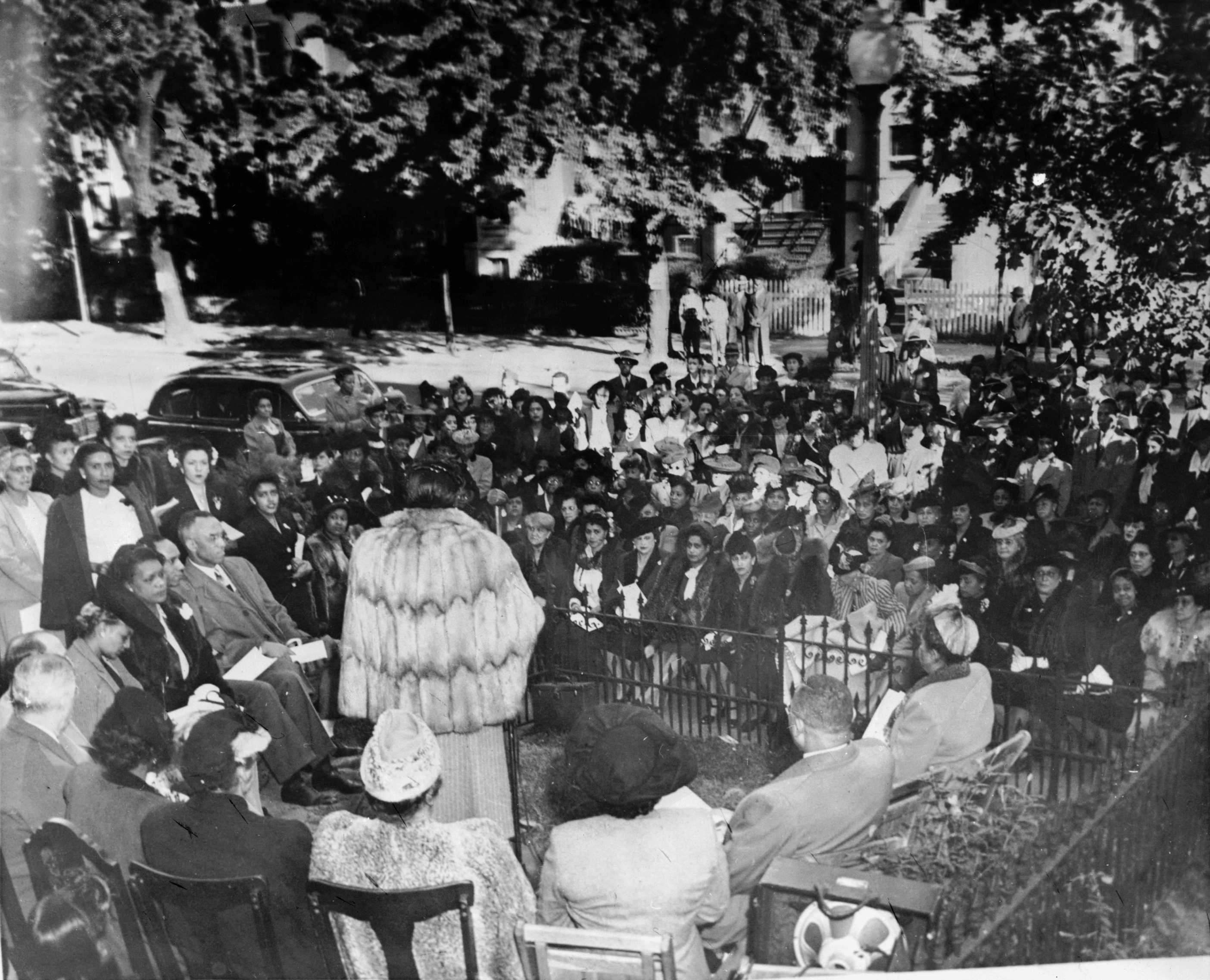 Photograph of Mary McLeod Bethune (with back to camera) speaking at the dedication of the National Council of Negro Women headquarters