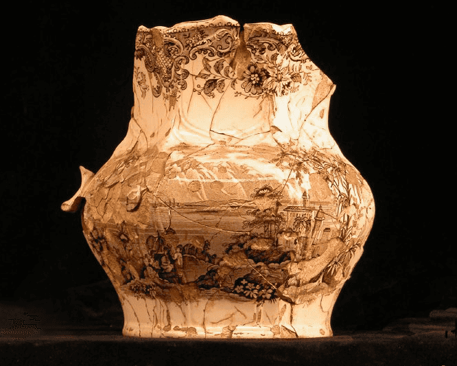 Photograph of a ceramic pitcher with brown floral motif at the top and a landscape at the bottom