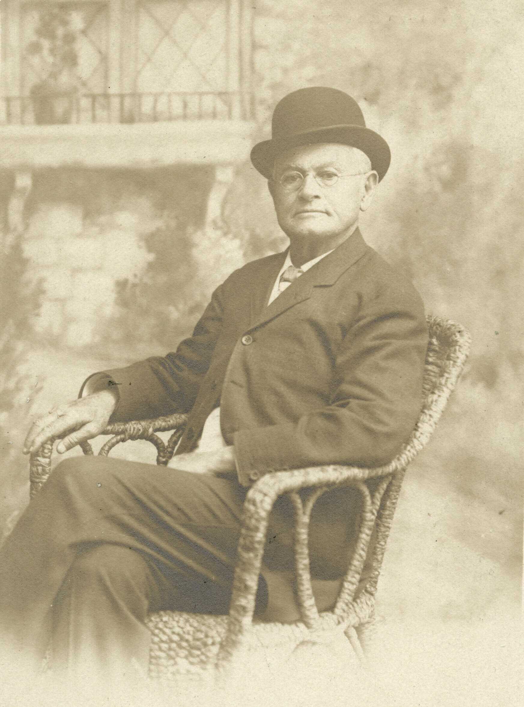 A faded sepia toned portrait of Robert Church sitting in the chair against a garden backdrop.