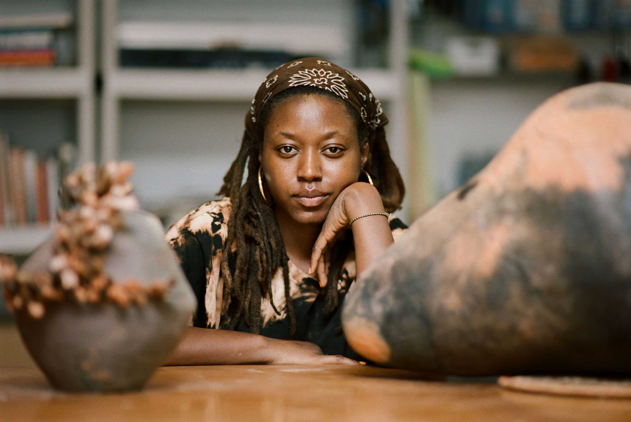 Portrait of a woman in a workshop, surrounded by pottery.