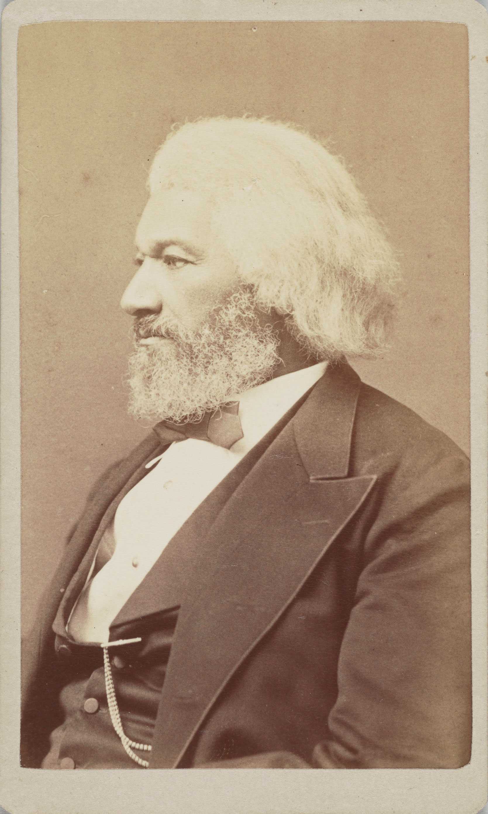 A carte-de-visite albumen print portrait of Frederick Douglass. Douglass sits in profile facing viewer's left wearing bowtie, jacket, and waistcoat. A watch chain hangs from the lapel of his waistcoat. The back of the card features the photographer's stamp. Stamp reads [Fassett / Artist Photographer, / 925 PENNA. AVENUE, / WASHINGTON, / D.C.]