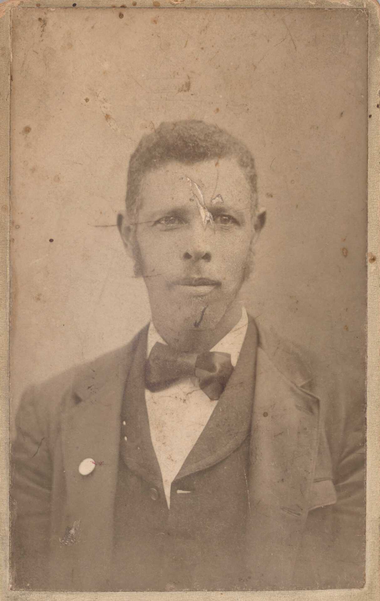 Carte-de-visite bust-length portrait of Marquis Peterson. He is wearing a dark-colored jacket, vest, bowtie and a light-colored shirt. He is looking at the camera and has large sideburns. A button can be seen on his right lapel. The back of the card has black construction paper adhered to it. On the back at the bottom of the card is a white label with back lettering that reads “Marcus Peterson.”