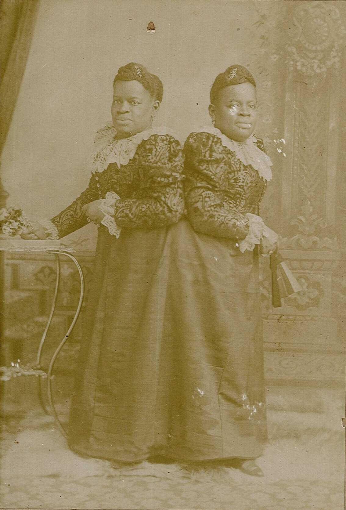 A worn, yellowed photo of Millie Christine McCoy in full length dresses.