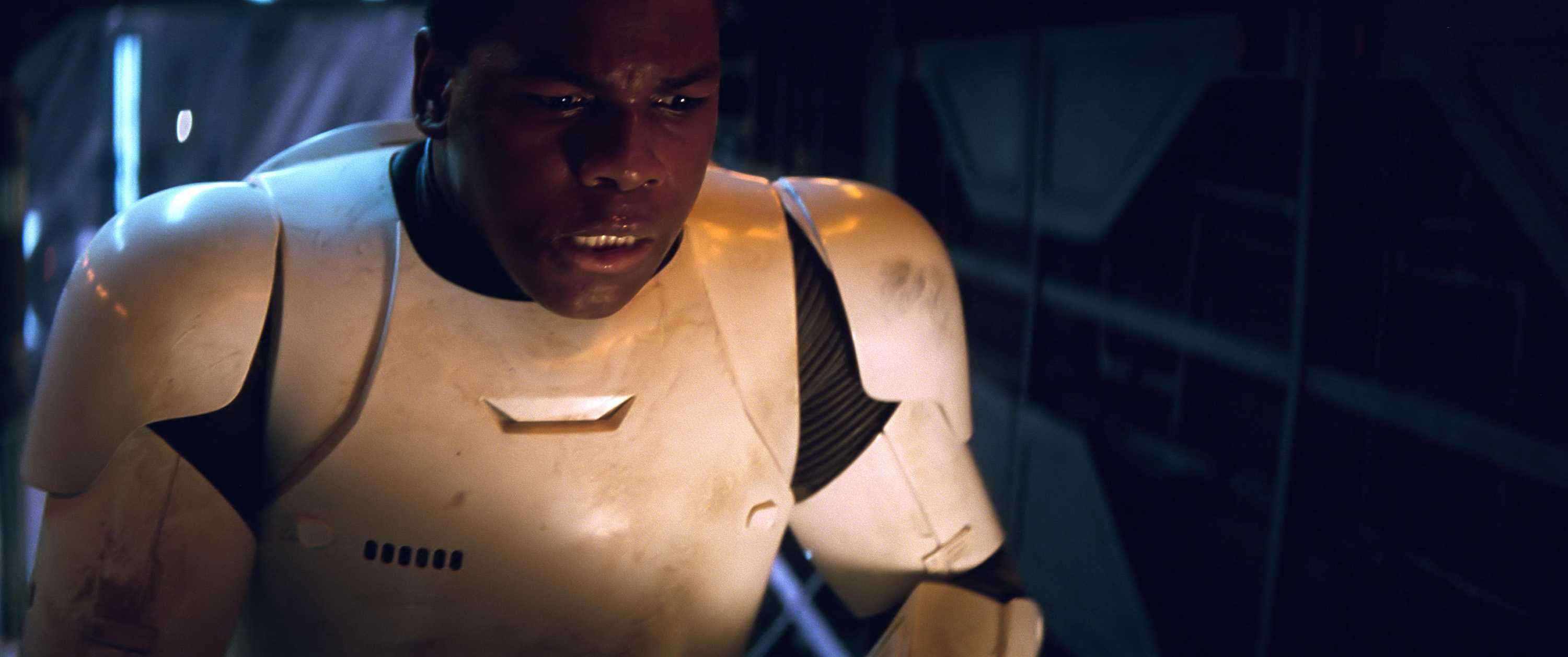 John Boyega in Star Wars dressed as a stormtrooper with his helment off. His mouth is slightly open, with a look of frustration.