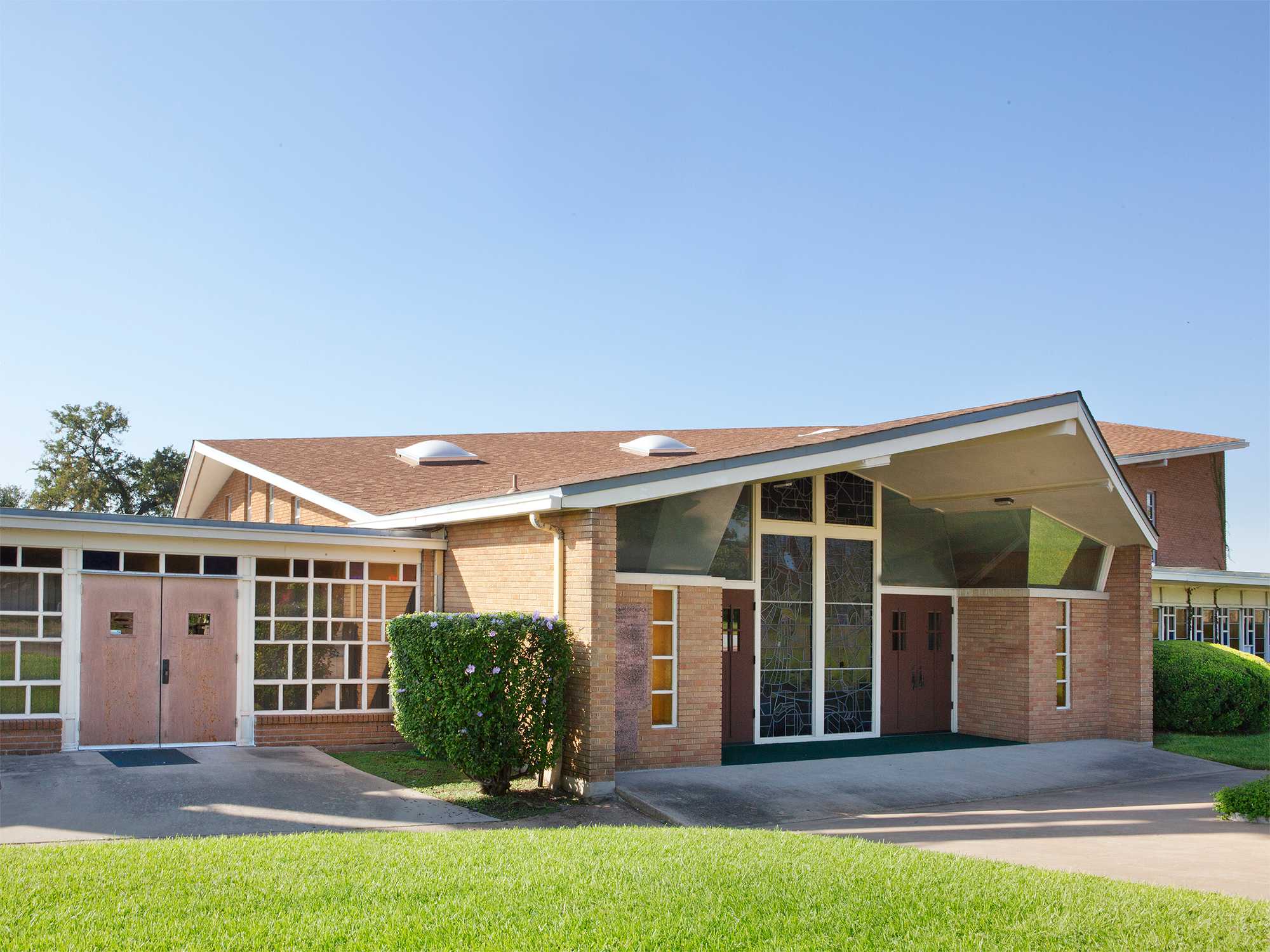 Modern brick building with slanted roof, skylights, and glass entrance.
