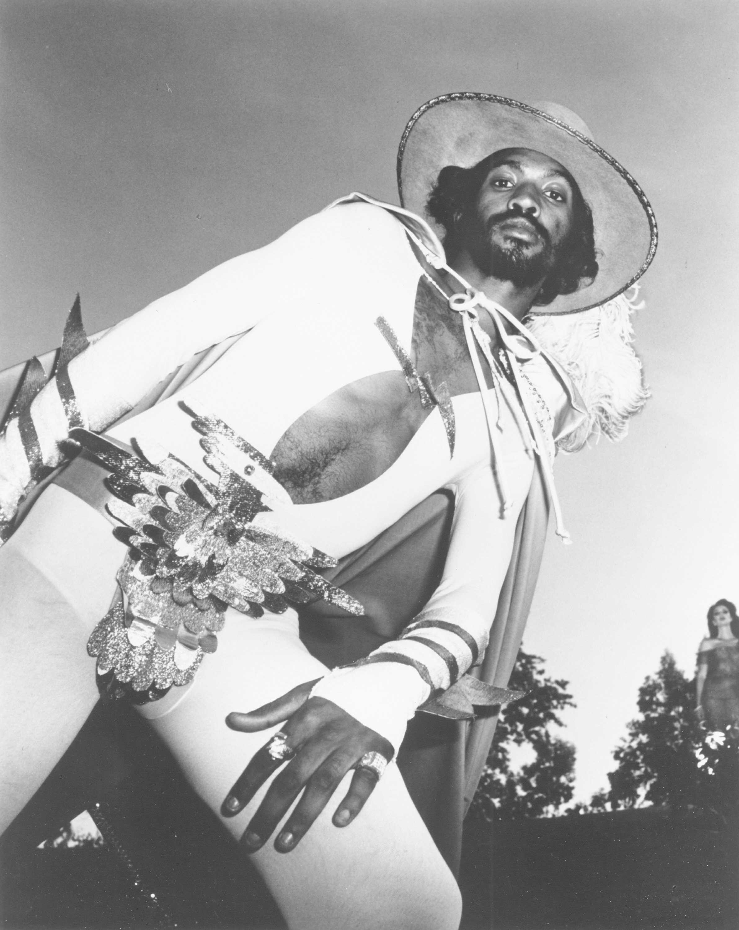 A black and white portrait of Eddie Hazel in a white disco suit, wearing a giant eagle belt.