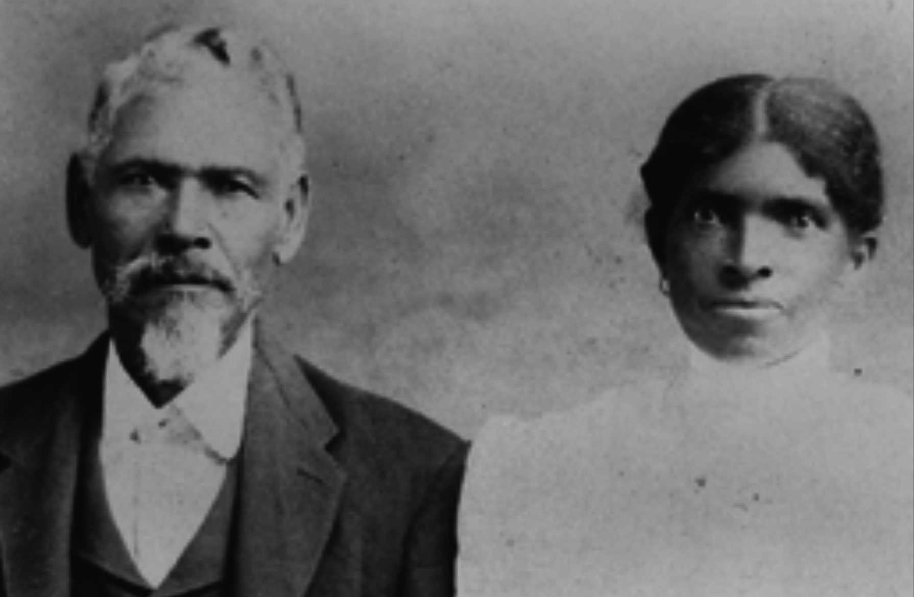 A blurry black and white photograph of Dick and Eliza Barnett. He is wearing a suit and she is wearing a white dress.