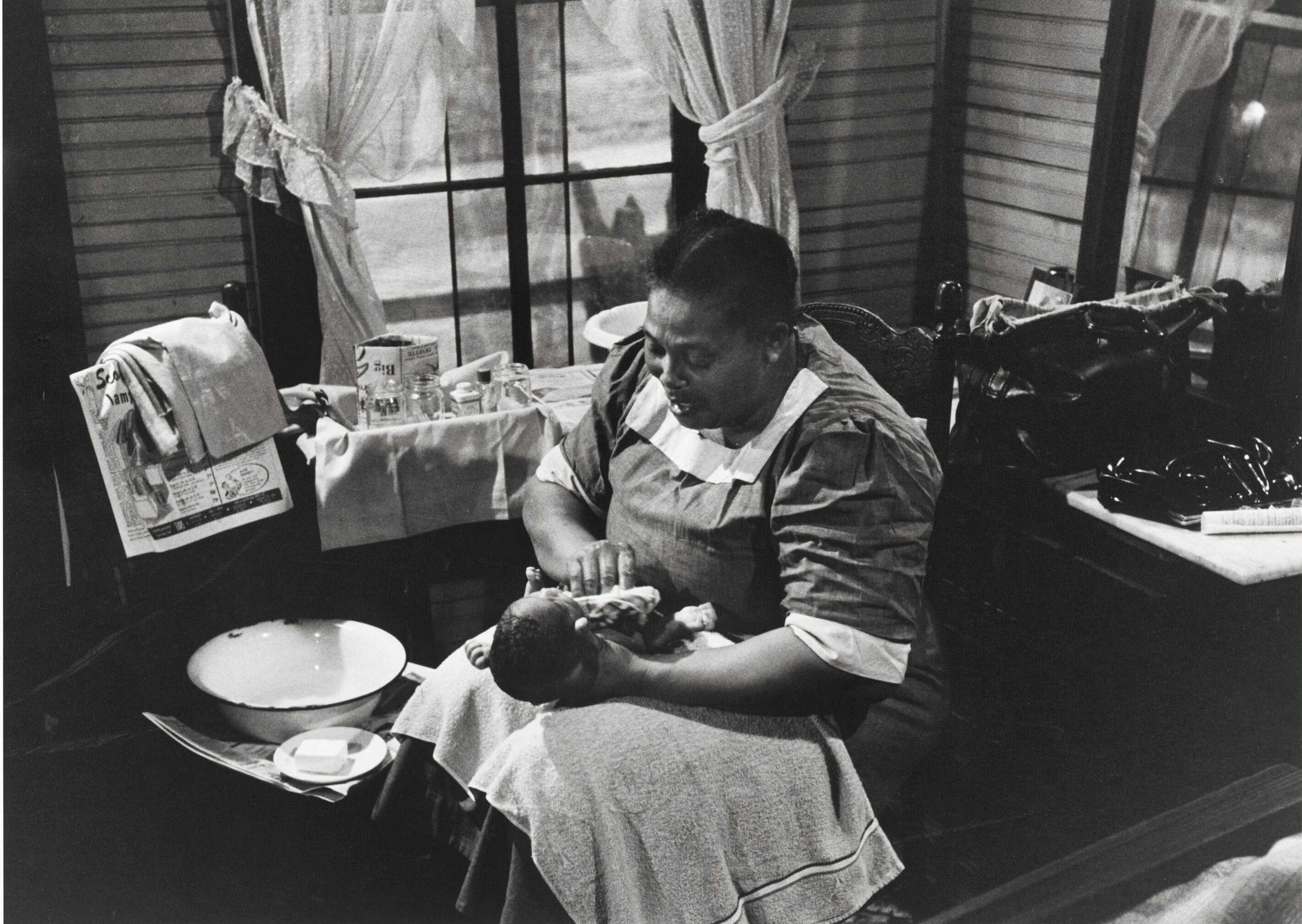 Black and white image of woman, Mary Francis Hill Coley, bathing a baby.