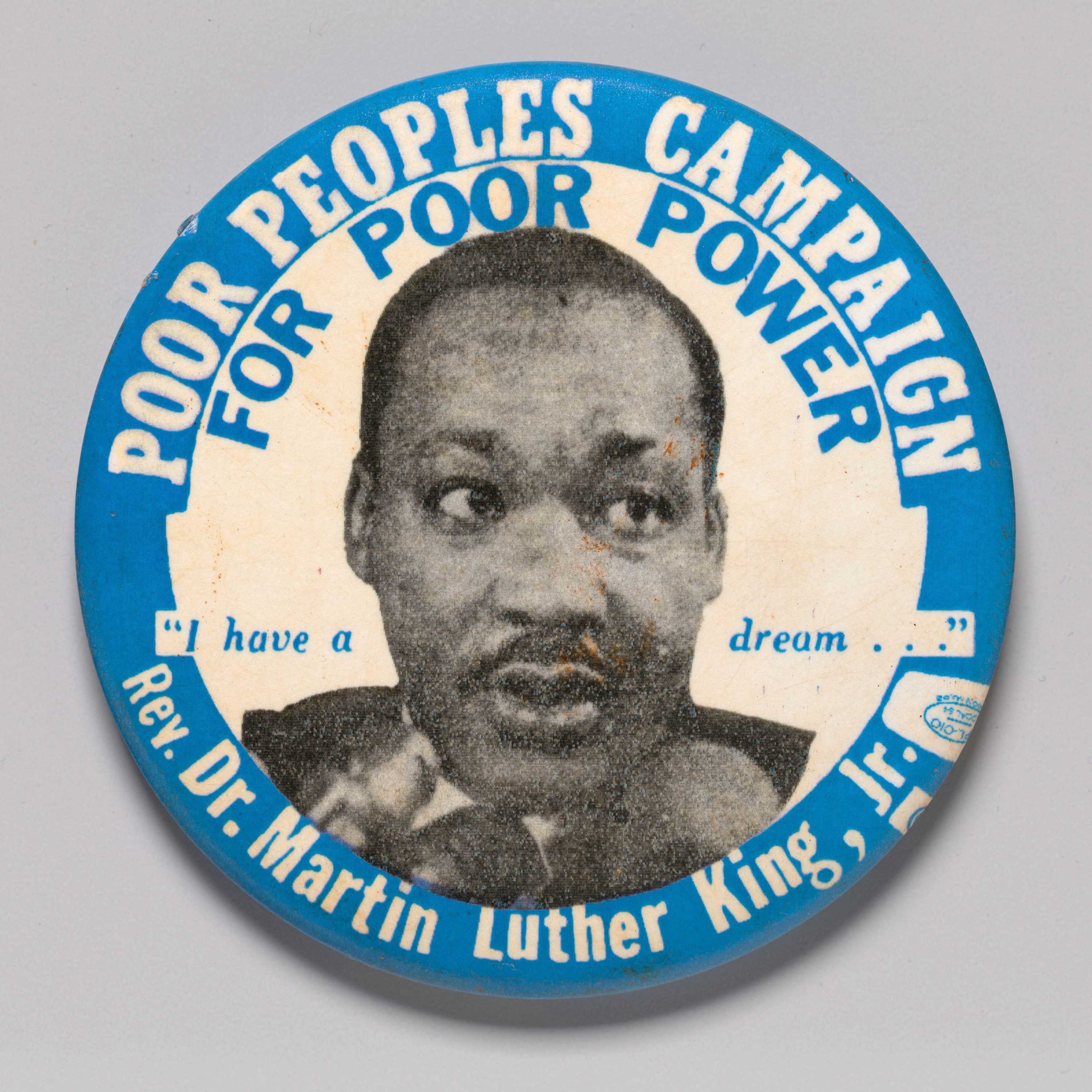 A round pinback button featuring a black and white portrait of Dr. Martin Luther King Jr. in the center. Printed above and around in white text on blue background is [POOR PEOPLES CAMPAIGN], directly below in blue text on white background is [FOR POOR POWER]. In the center, divided by the portrait are the words ["I have a dream..."] in blue text. Below the portrait, in white text on blue background is [Rev. Dr. Martin Luther King, Jr.], followed by a union printer's symbol.