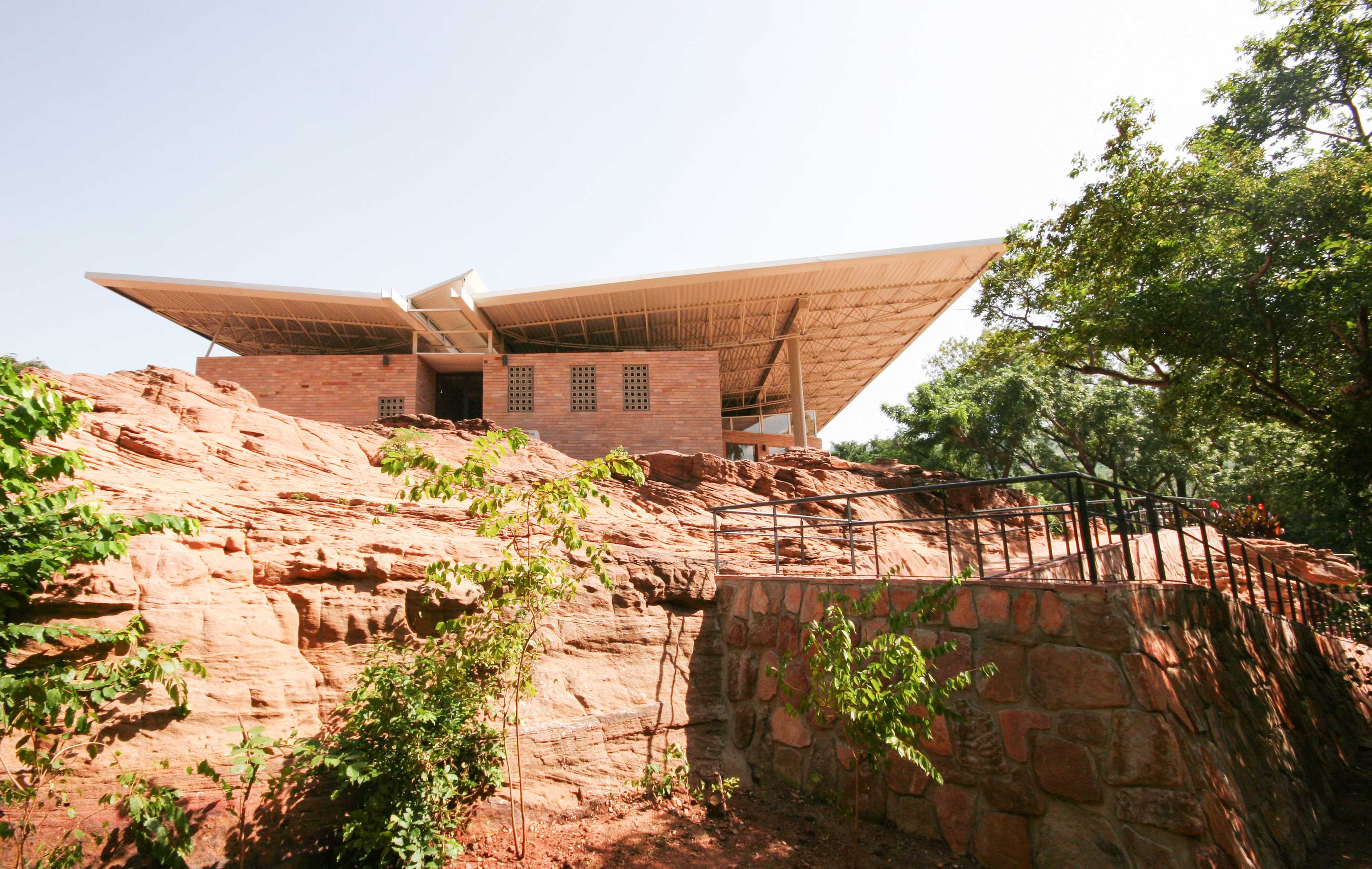 Within the National Park of Mali, a small stone build sits within the terrain with an oversized roof.