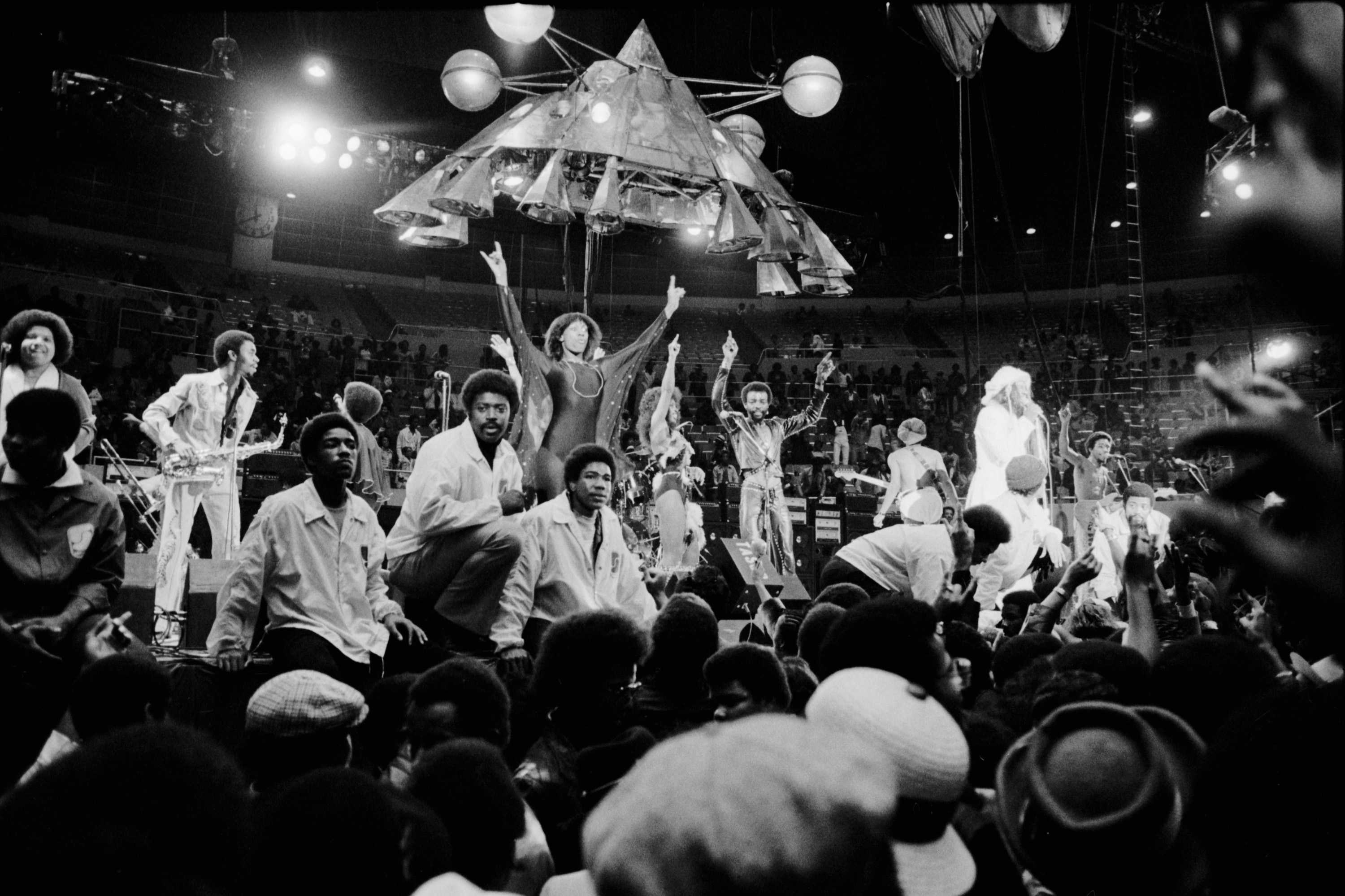 Parliament Funkadelic on stage The Mothership hovering above them. Security guards separate the audience.