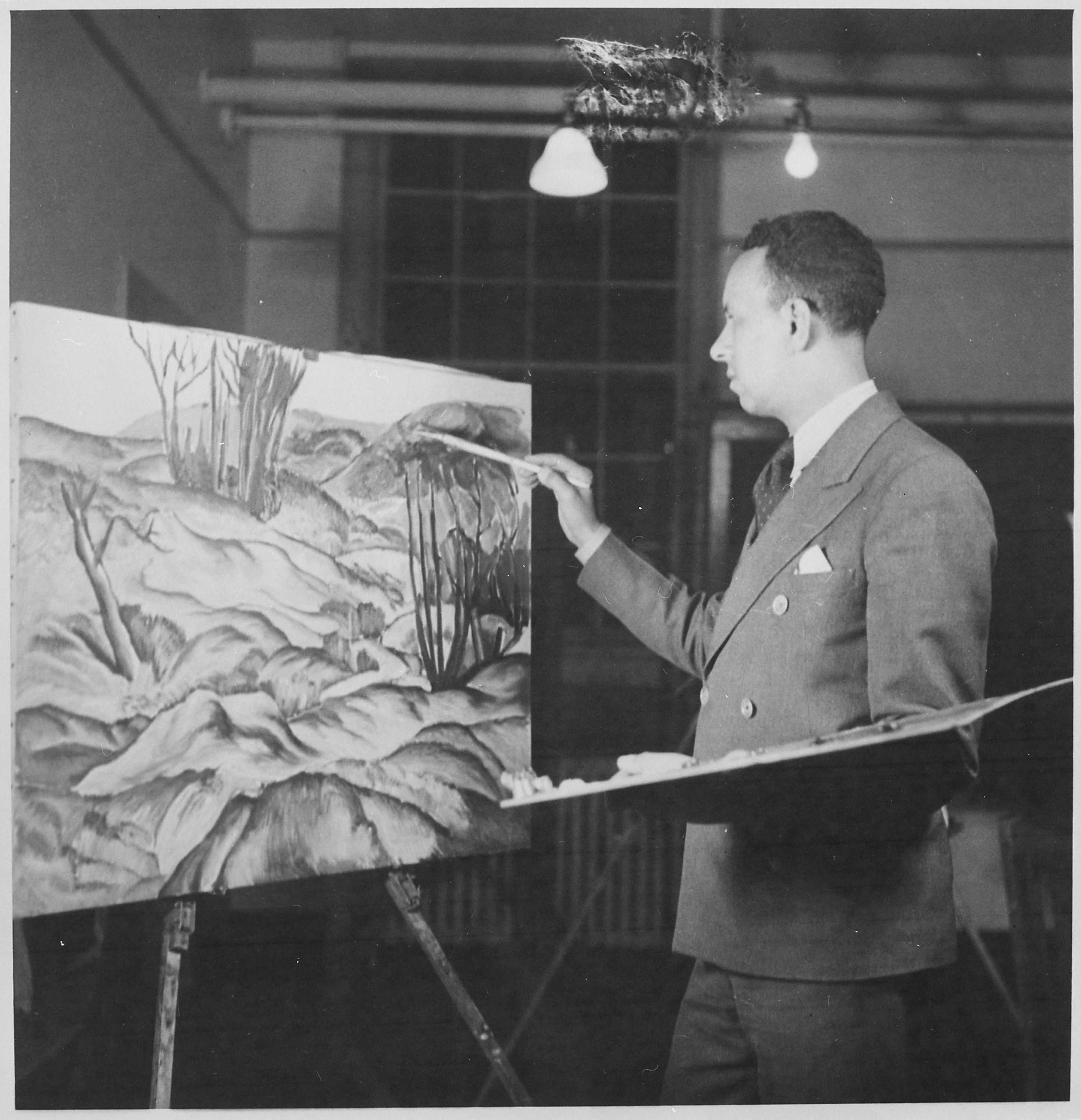 Black and white photograph of a man painting on a canvas.