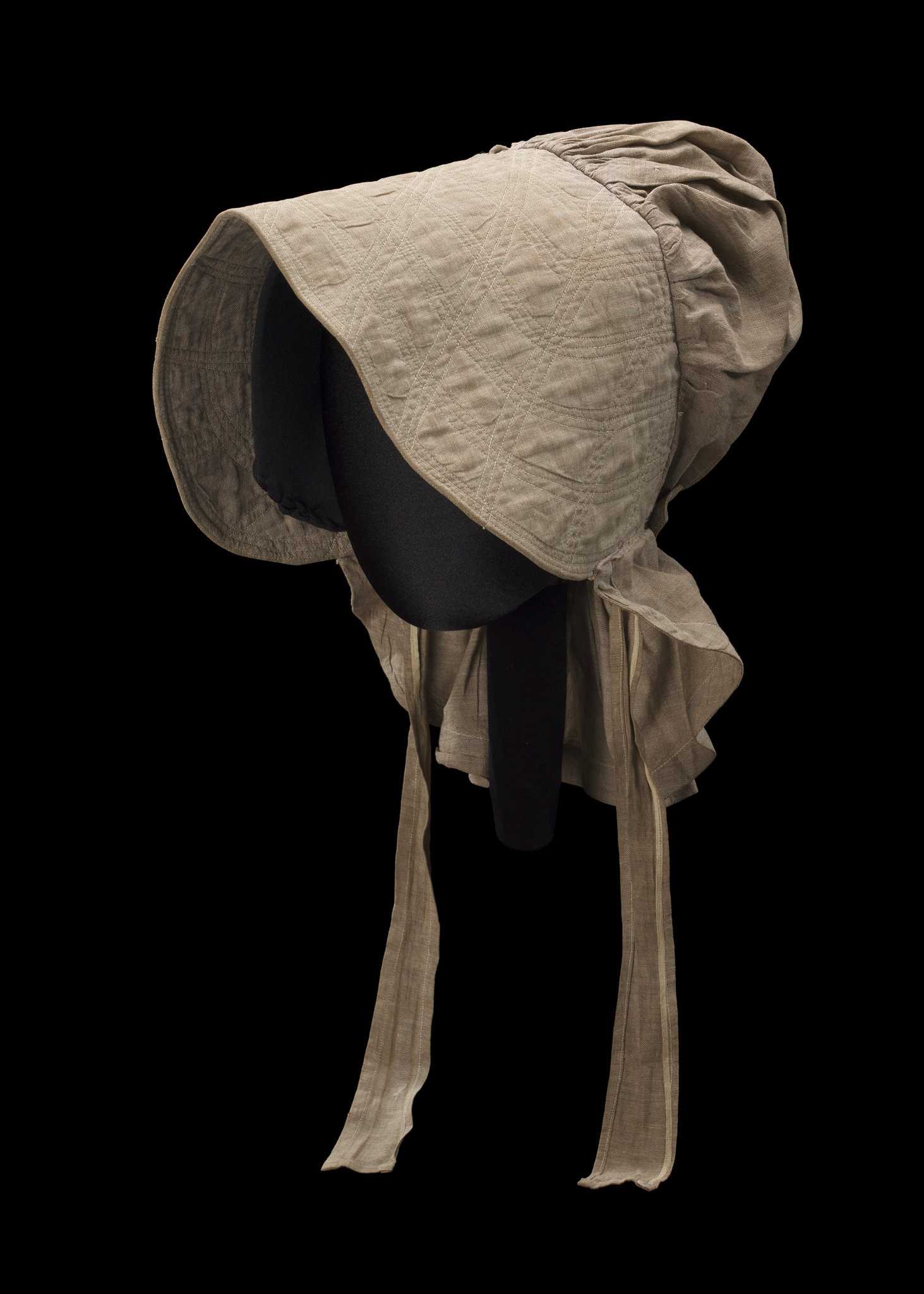 A taupe-colored bonnet with cross-stitched brim and chin straps believed to have been worn by Martha Miller Barnes while she was enslaved as a field laborer by E.A.J. Miller on his plantation near Waterproof, Louisiana.

The bonnet is a linen and cotton blend plain weave fabric. It has a short skirt that is cinched on the underside with a tied string. There is a decorative flap over the gathered portion that buttons on one side with a mother-of-pearl button. There are self-fabric short ties sewn at each interior side. The front of the bonnet has three layers, the brown linen/cotton blend is used as the facing and the lining, and there is an additional layer of  plain undyed muslin that is peeking out on the underside of the seam. The front is heavily stitched with off-white thread to make it stiff. It is machine sewn. There are some minimal brown spot stains concentrated in a scattered manner on the underside of the brim. The brim is creased at the center from being folded.