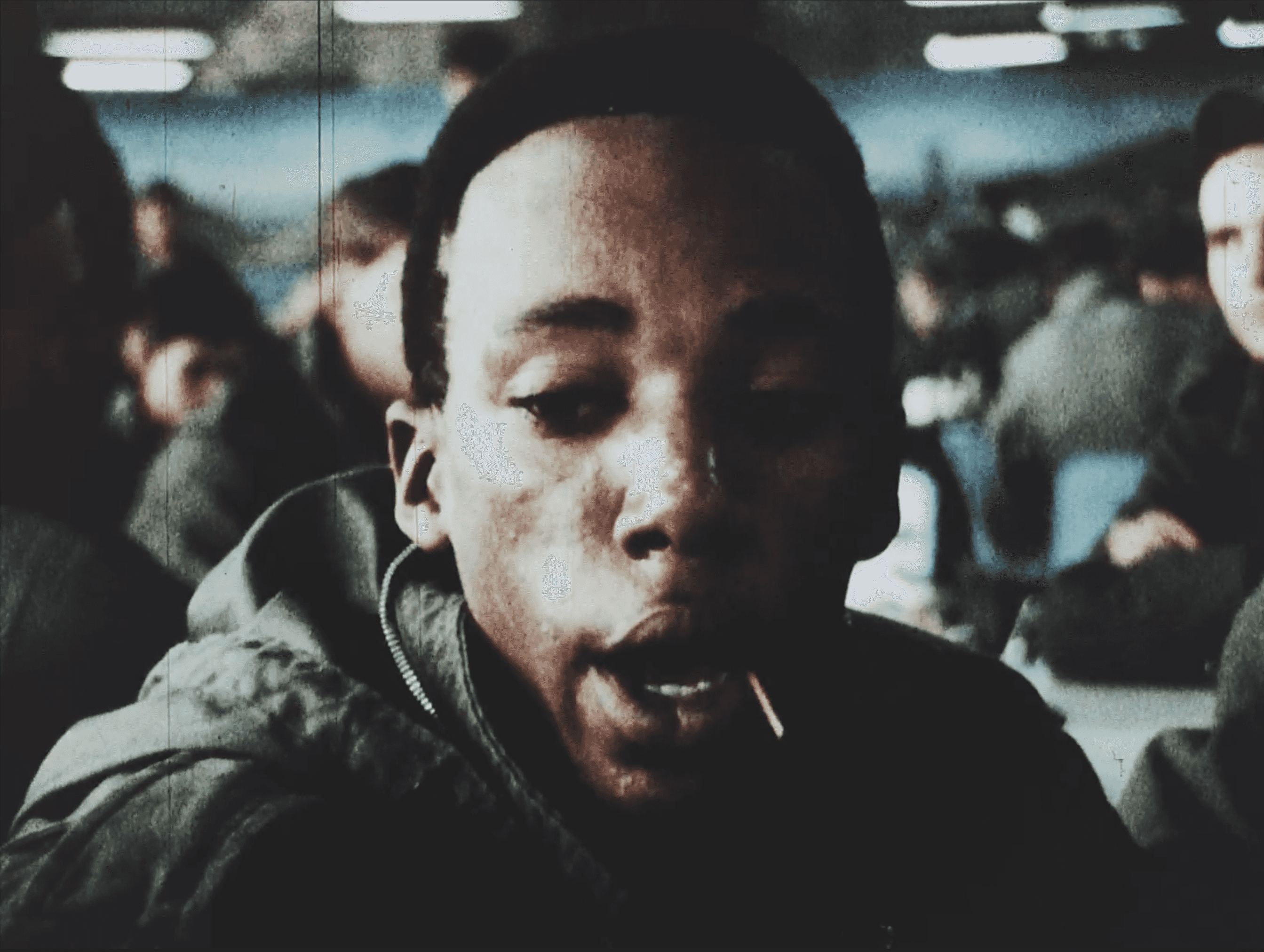 In a crowed cafeteria, a man is talking with a toothpick in his mouth.