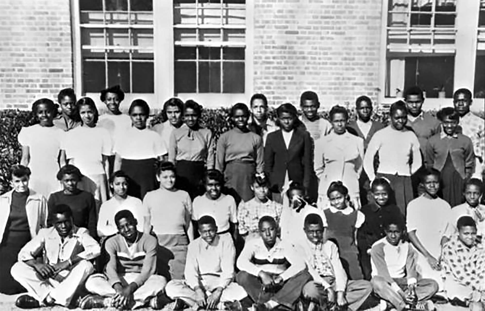 Photo of a group of children and teenagers posing in front of a brick building.