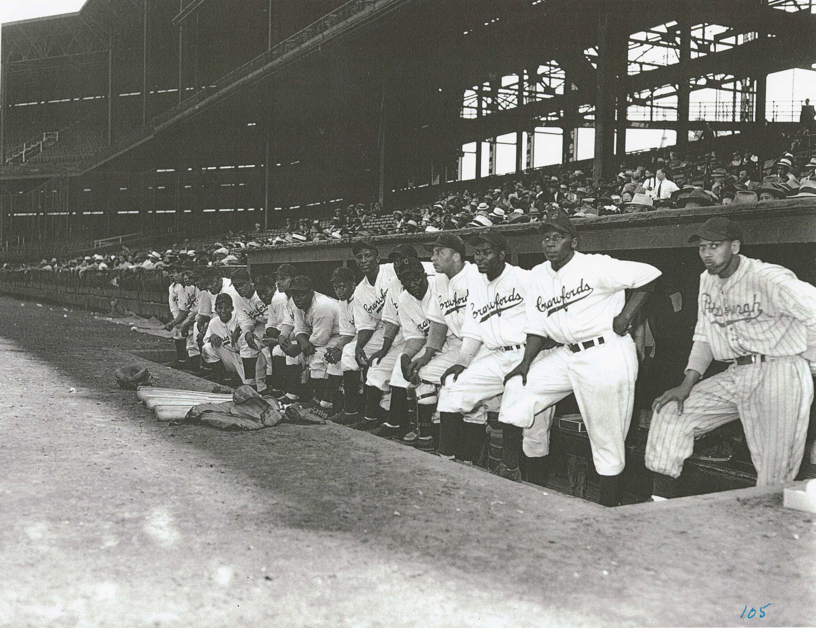 A black and white photograph of the Pittsburgh Crawfords baseball team in dugout at Forbes Field.