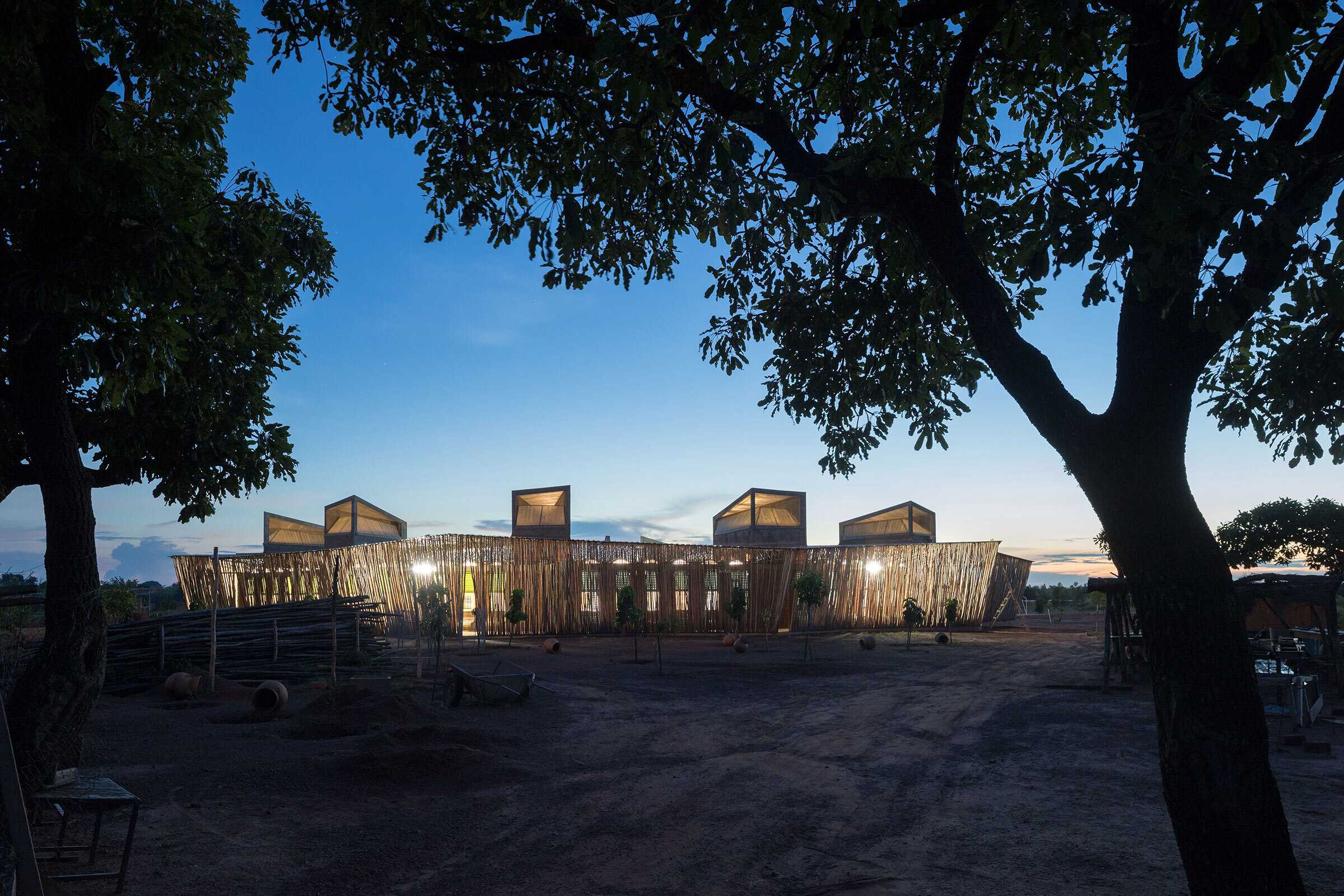 A landscape view of Lycée Schorge Secondary School at dusk. The school's is dimily light within.