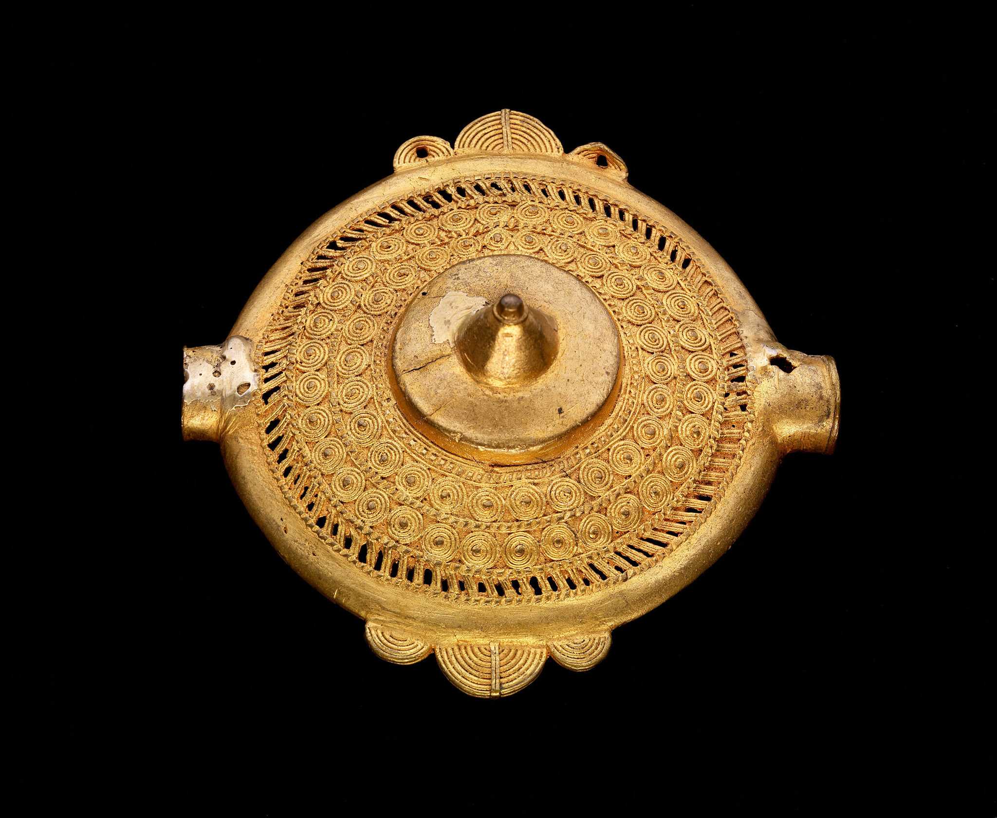 A gold pectoral disc with intricate spirals surrounding the middle point.