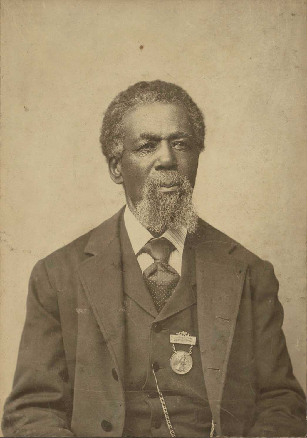 A cabinet card of Thomas Peterson. Peterson is looking at the camera and wearing a three-piece suit with a medal attached to the left side of the vest. The medal was presented to Peterson in 1884 by the residents of Perth Amboy, N.J. in recognition of his status as the first African American voter in the United States under the provisions of the Fifteenth Amendment. The albumen print is attached to a stiff card backer with wear showing around the edges. There is a printed label on the verso that reads, "Inscription on the Medal. Presented by citizens of Perch Amboy, N.J., to Thomas Peterson, the first colored voter in the United States under the provisions of the Fifteenth Amendment, at an election held in that city March 31st, 1870." The cabinet card was printed as a memento for the medal presentation ceremony.