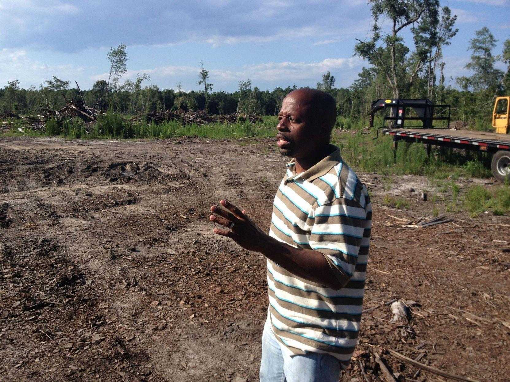Louis Manigault Jr. talking in a dirt field with trees and greenery behind.