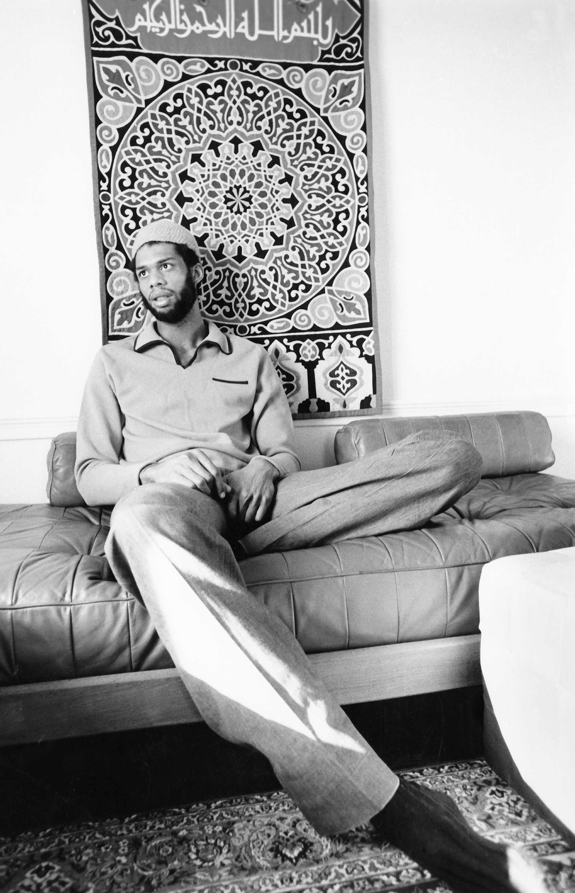 Black and white photograph of Kareem Abdul-Jabbar at home sitting on a couch