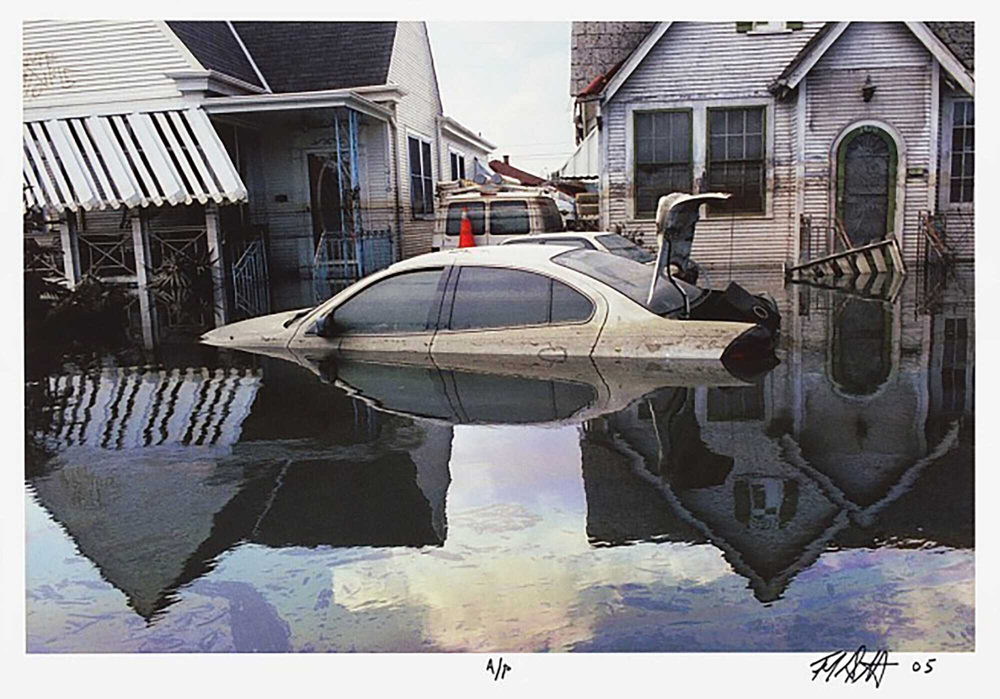 A color photograph of flooding in New Orleans after Hurricane Katrina. At center is a car, a four door sedan with its trunk open, abandoned in water up to the door handles.