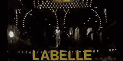 Labelle in yellow typography overlay on the bottom of the screen while Labelle stand on stage ready to preform.