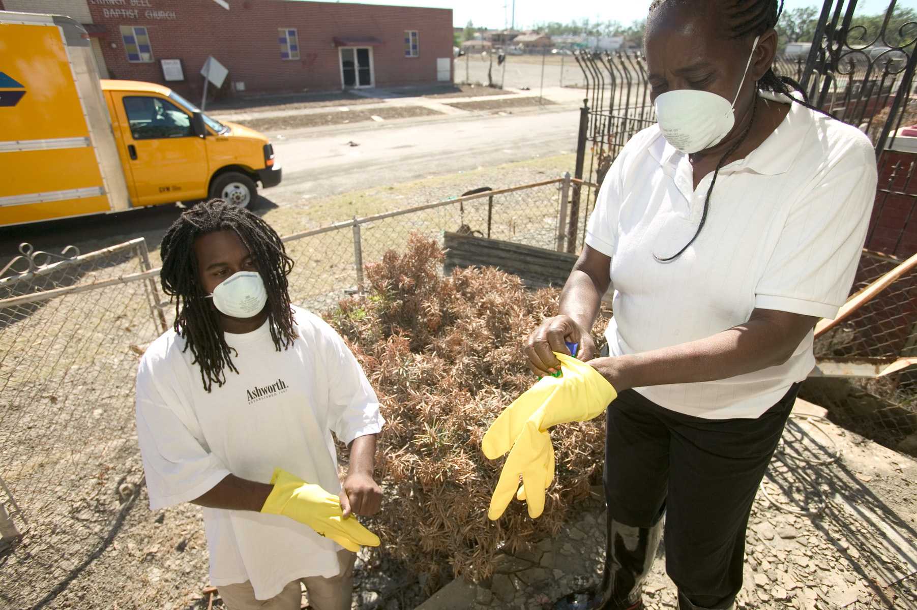 Two people putting on gloves outside of their home in New Orleans.
