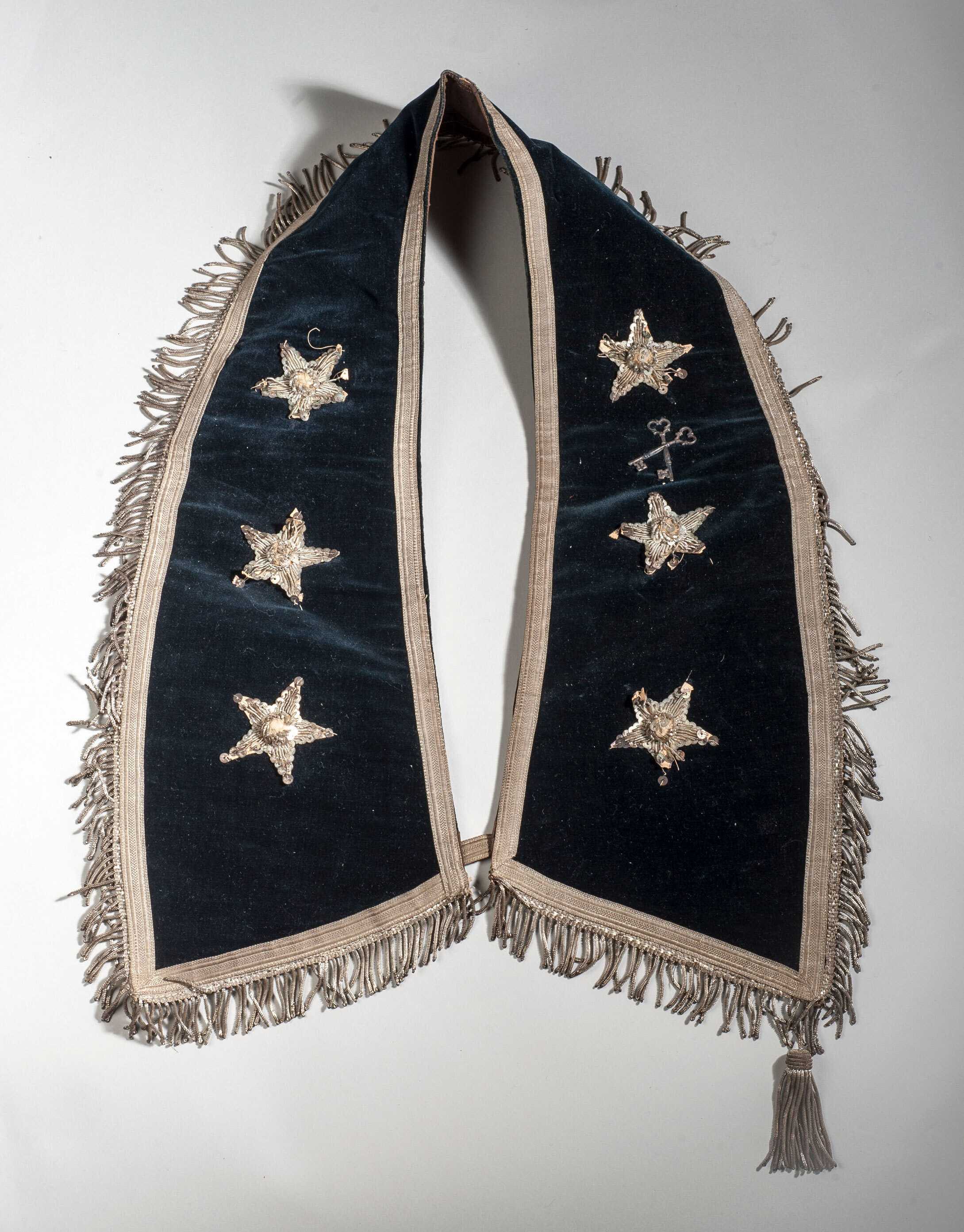 Blue velvet ceremonial collar embroidered with three stars, stacked one on top of the other on each side of the collar.   The collar  is trimmed with off white fringe and and one tassel.  There are two criss crossed keys embroidered between the first and second stars on the right hand side of the collar.