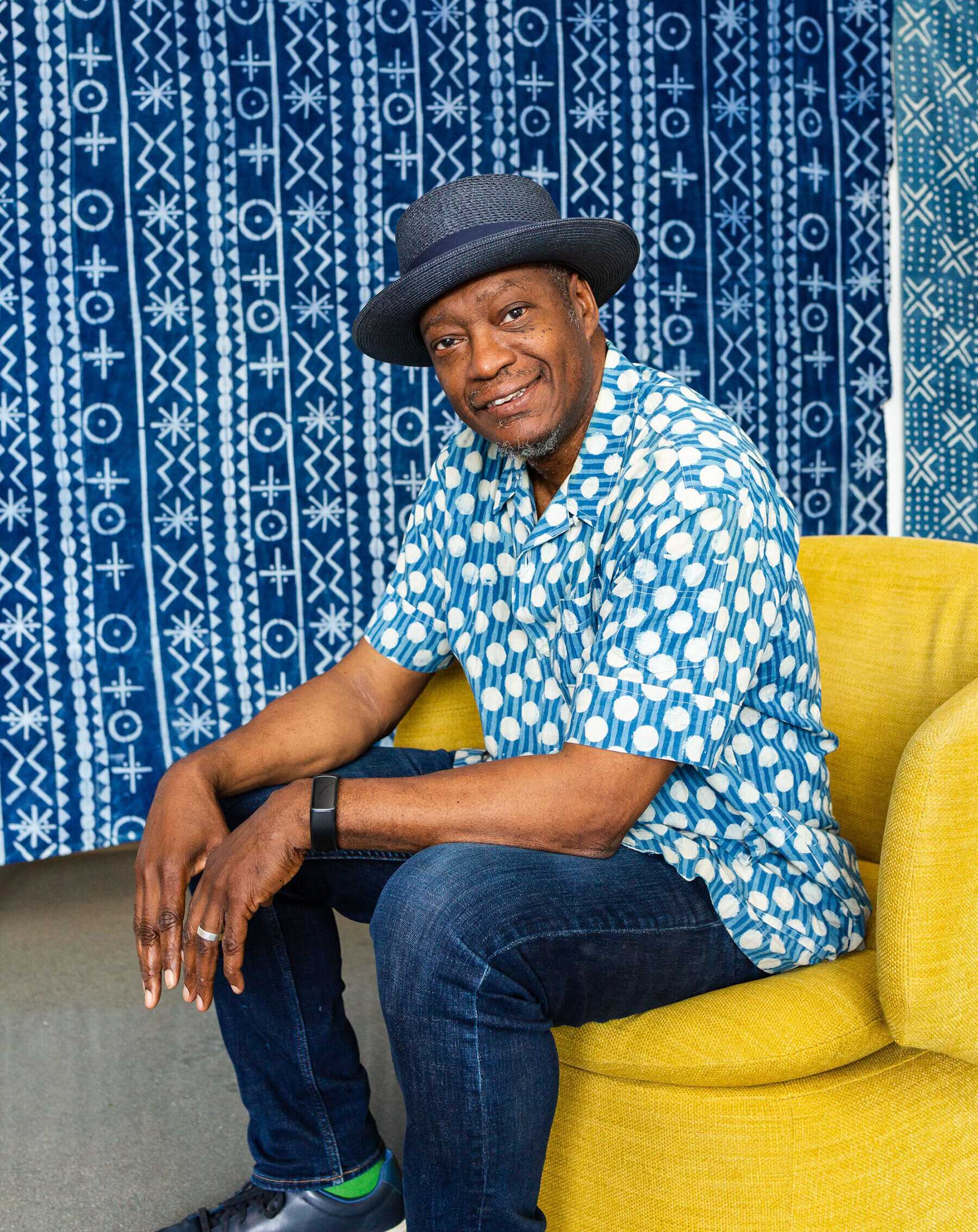 Color photograph of artist Daniel Minter seated in a yellow chair.