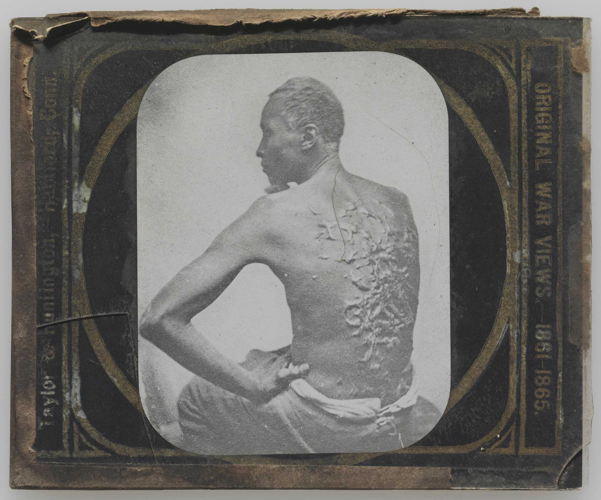 A glass plate photographic "magic lantern" slide depicting the bare back of an enslaved man with multiple raised scars. The slide has a black and gold paper sleeve and is in a plain wooden slide mount. There is a short crack in the lower left corner of the upper glass plate. The image depicts a man, often identified as "Gordon," or "Private Gordon," and sometimes as "Peter," seated with his shirtless back to the camera. His proper left hand is on his left hip, his elbow extended, and his face is turned to the left. Along the right side of the sleeve is printed [ORIGINAL WAR VIEWS - 1861-1865]  and on the left is [Taylor & Huntington - Hartford, Conn.].
