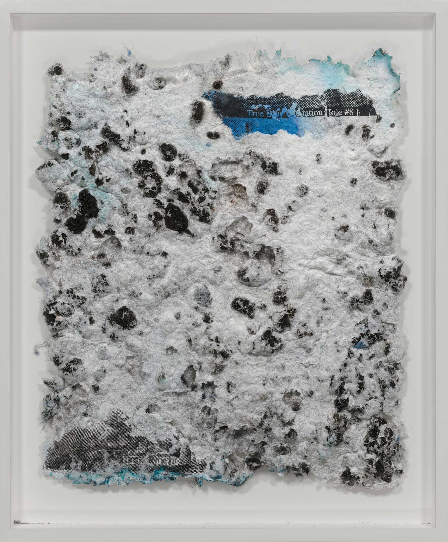 Mixed media artwork featuring textured white and black surface with hints of blue and text elements embedded.