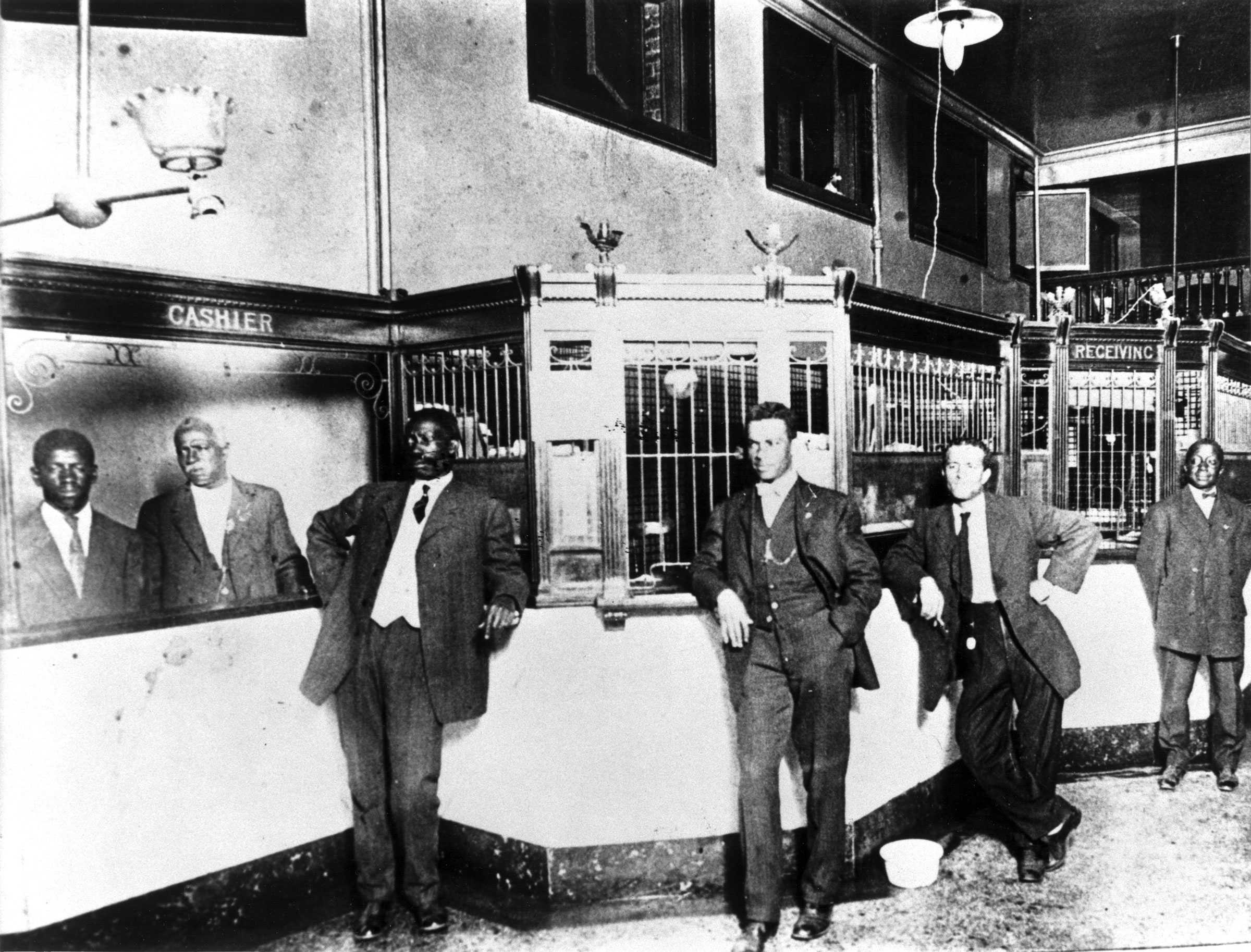 African American Banks stand in the lobby and behind the cashier of the Penny Savings Bank