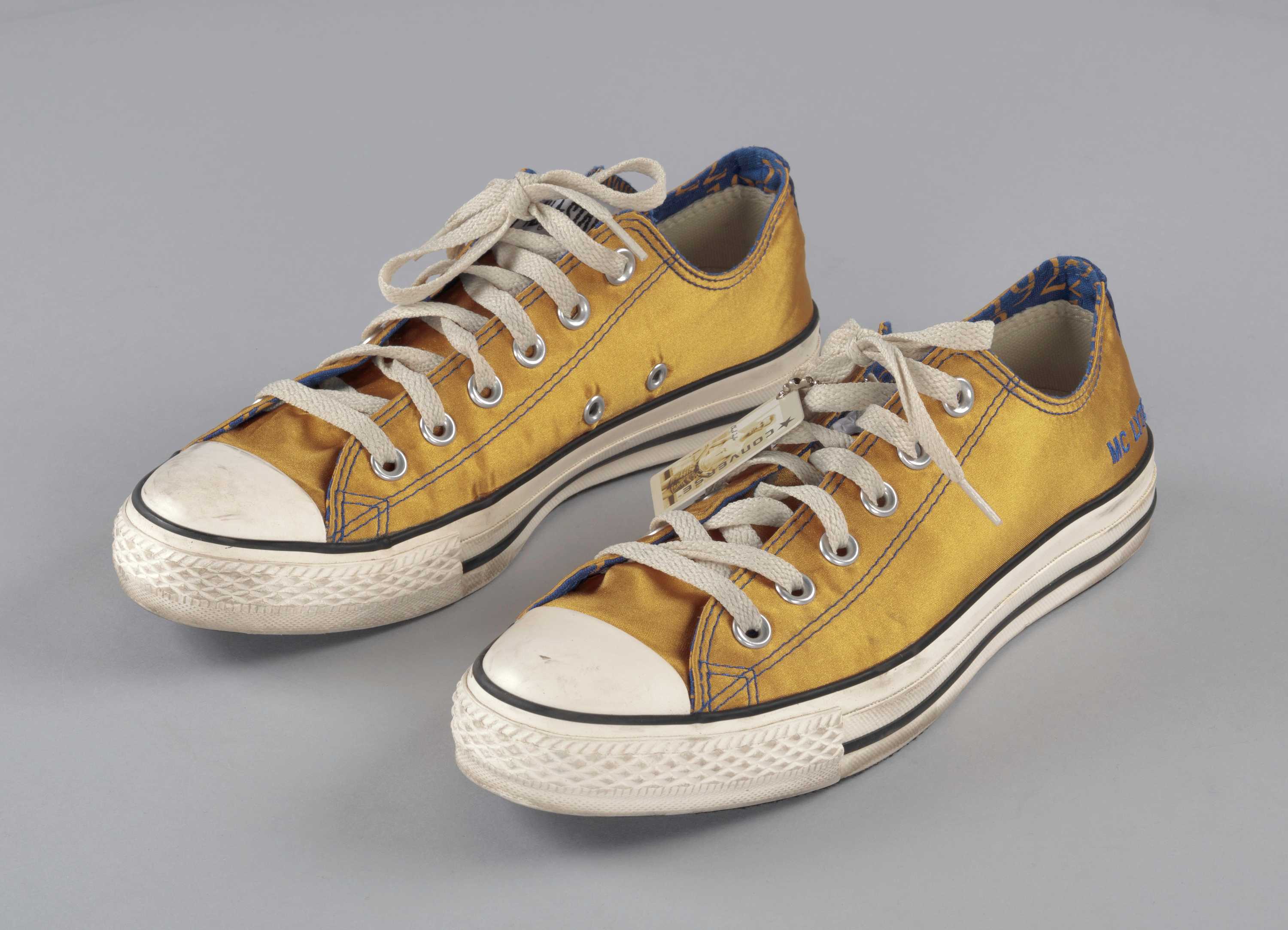 A pair of gold and blue satin Converse sneakers customized for Sigma Gamma Rho sorority member MC Lyte.